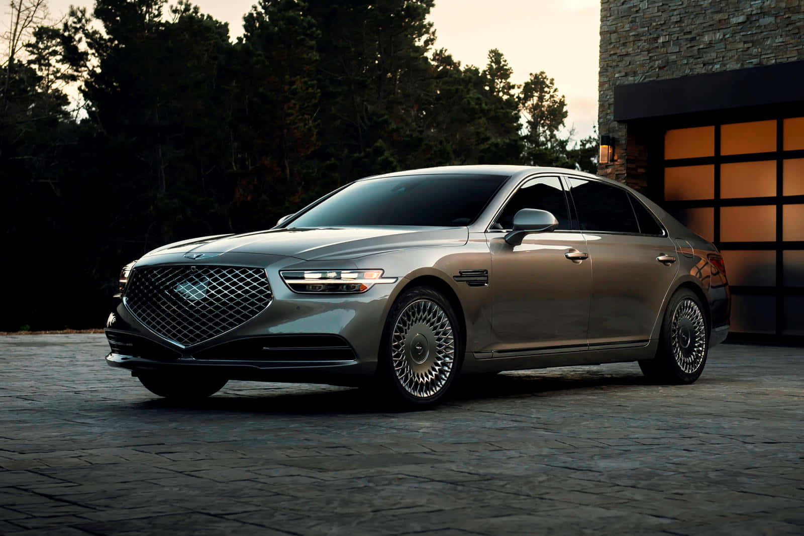Genesis G90 桌布 壁紙 — 一輛時尚的銀色豪華轎車停泊在黃昏時分現代石屋旁的石頭車道上。
