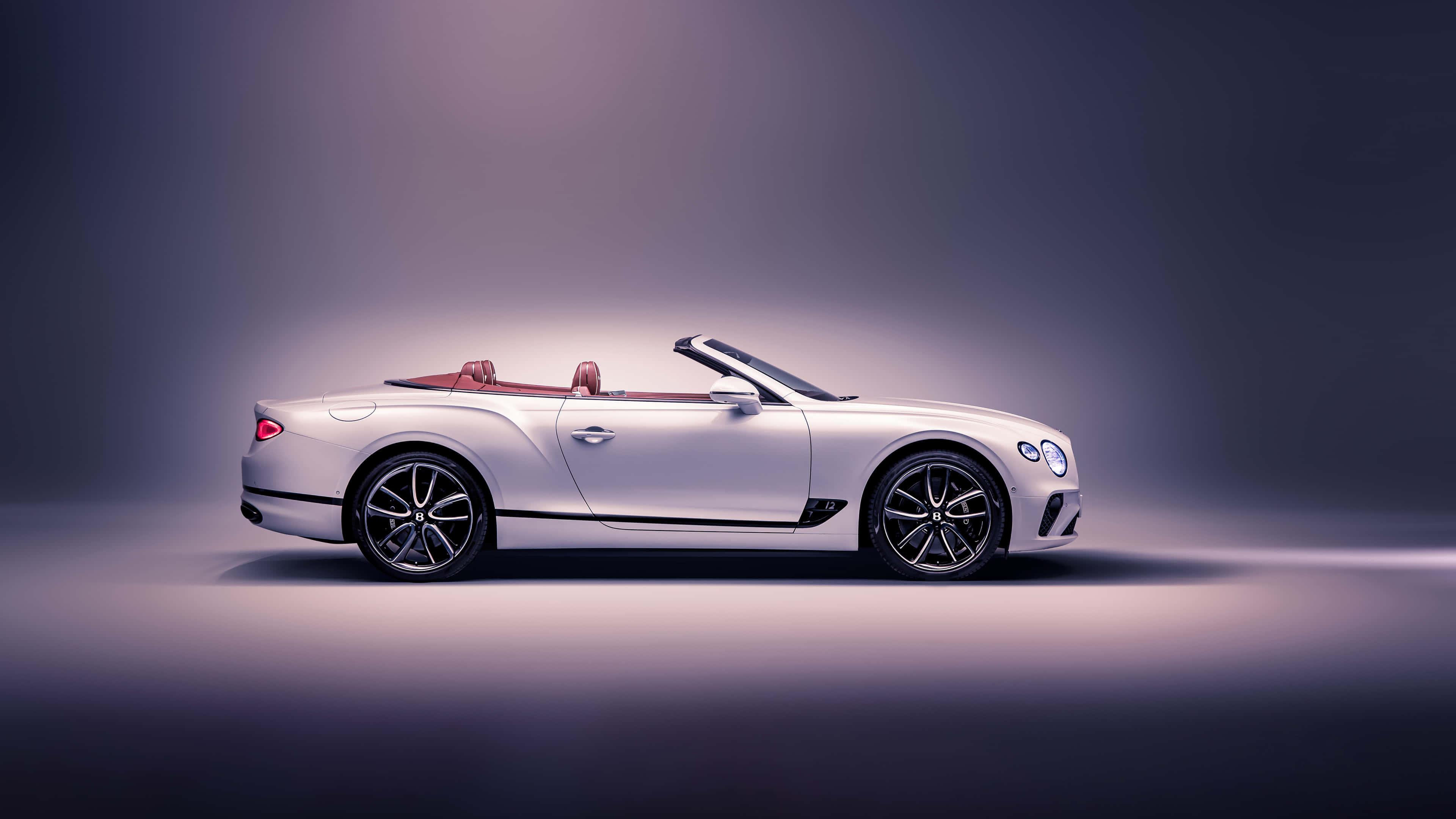 Bentley Continental Gt Convertible 桌布 壁紙 — 一輛時尚的銀色賓利開篷車配紅色皮革座椅，在柔和紫色燈光的攝影棚中展示。