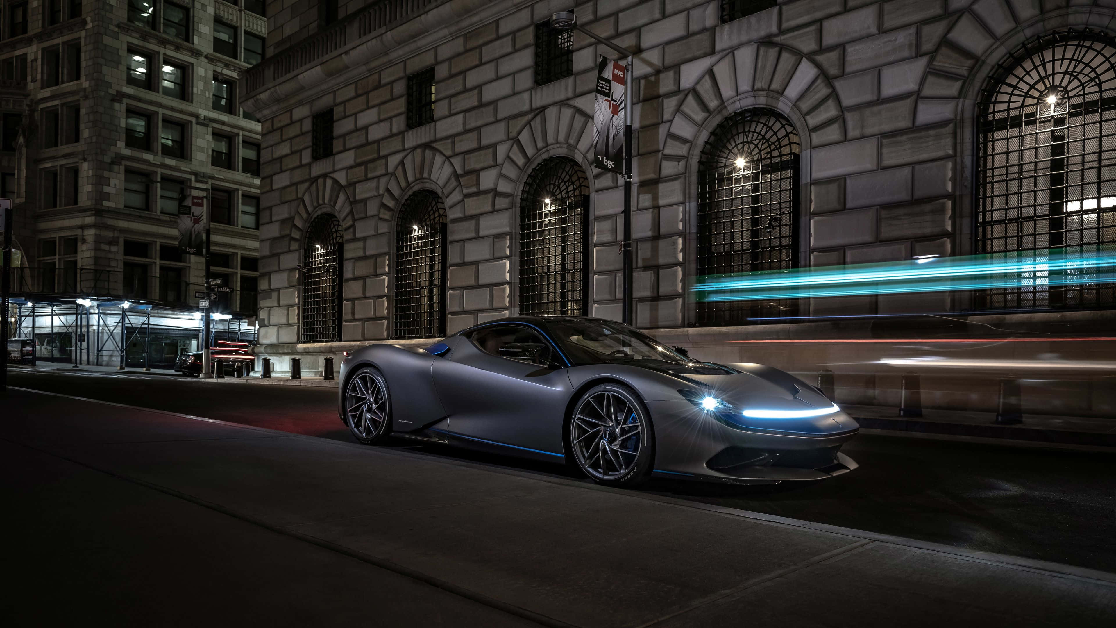 Pininfarina 桌布 壁紙 — 一輛時尚的銀色跑車在夜晚穿梭於霓虹燈照亮嘅城市街道，伴隨住來往車輛嘅動態模糊痕跡。