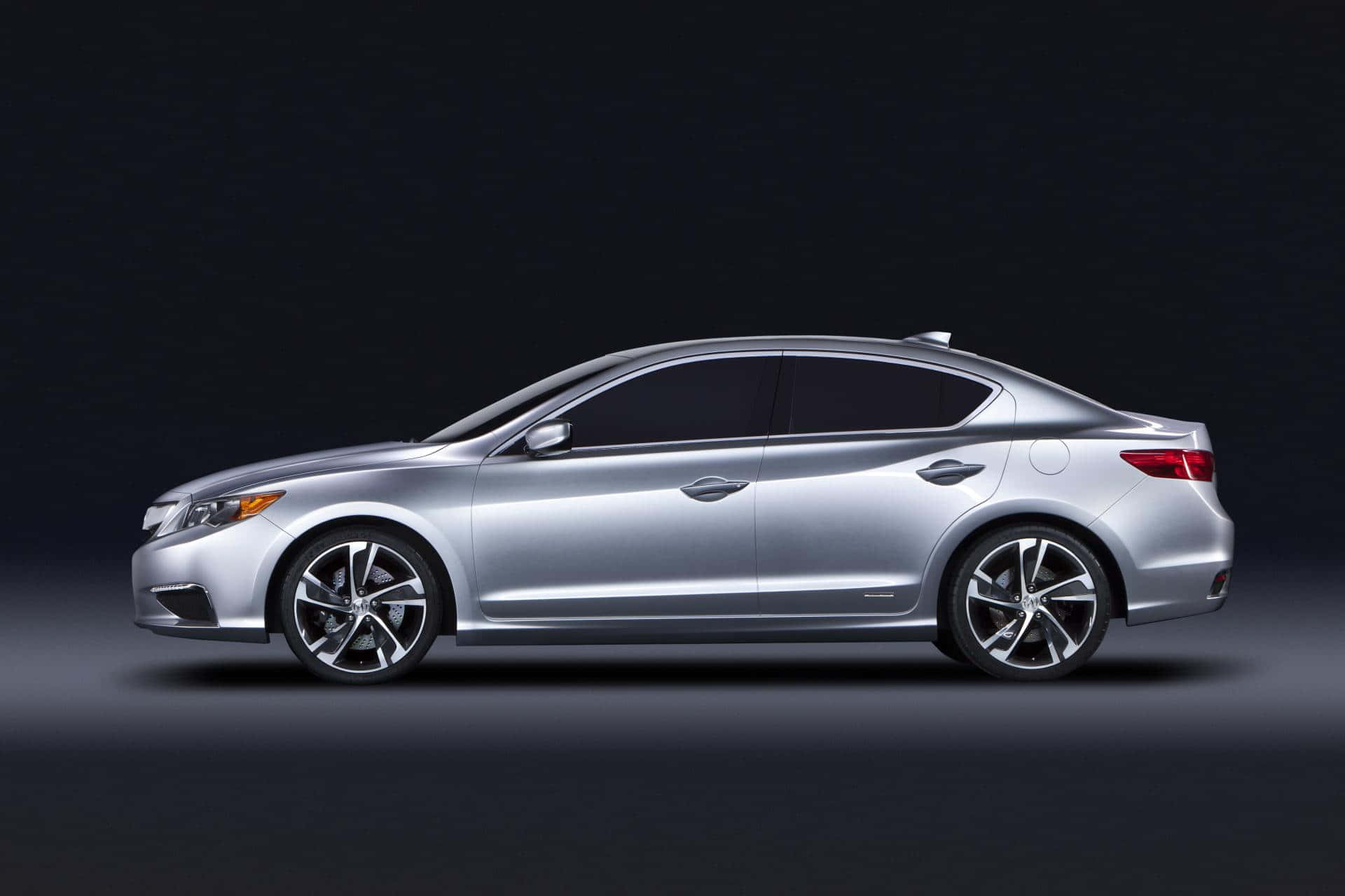 Acura Ilx 桌布 壁紙 — 一輛時尚的銀色轎車在黑暗的攝影棚背景下以側面輪廓展示，配以戲劇性燈光。