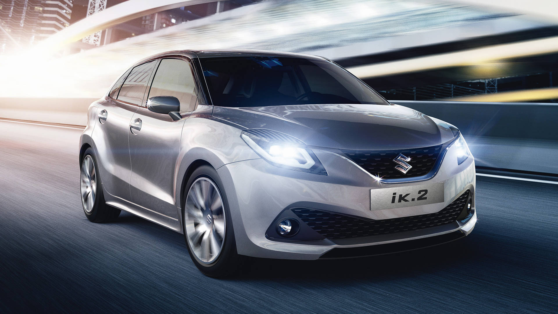 Suzuki IK 2 壁紙 — 一輛時尚的銀色鈴木 iK.2 在充滿未來感的城市景觀中疾馳，伴隨著發光的燈光和動態模糊效果。