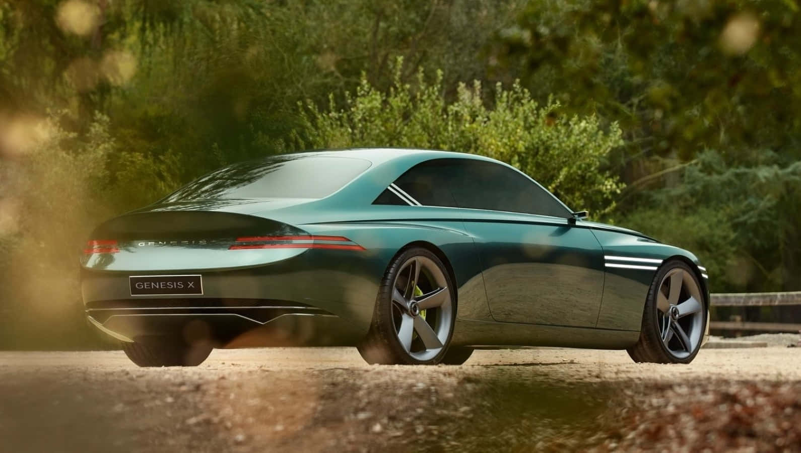 Genesis X Concept 桌布 壁紙 — 一輛時尚的青色Genesis X概念車沿著森林道路行駛，金色陽光穿過樹林灑落。