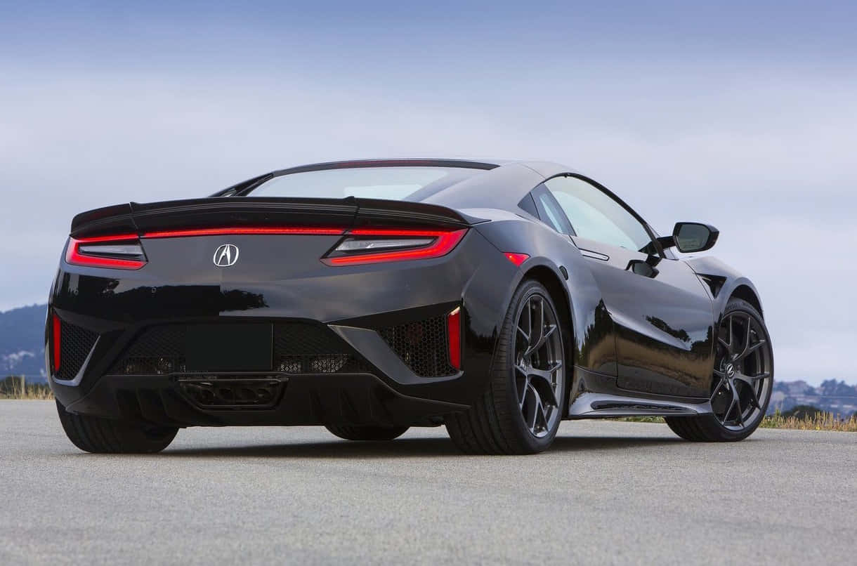 Honda Nsx 桌布 壁紙 — 一輛時尚的黑色Acura NSX跑車，帶有發光的紅色尾燈，停在陰天天空下的開放瀝青路上。
