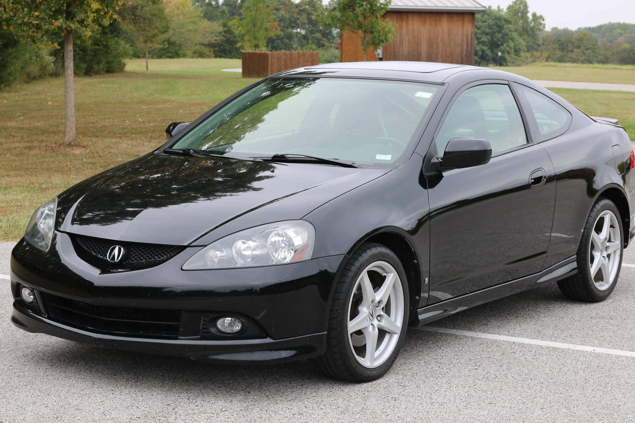 Acura Rsx 桌布 壁紙 — 一輛時尚的黑色Acura TSX雙門轎跑車停在瀝青路上，背景有樹木和一個木棚。