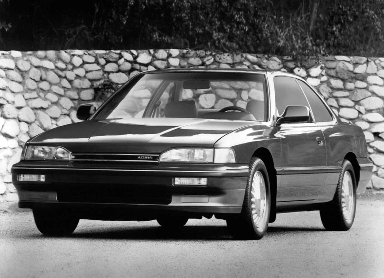 Acura Legend 桌布 壁紙 — 一輛時尚的黑色Acura轎跑車停在質感石牆前，經典黑白照片。