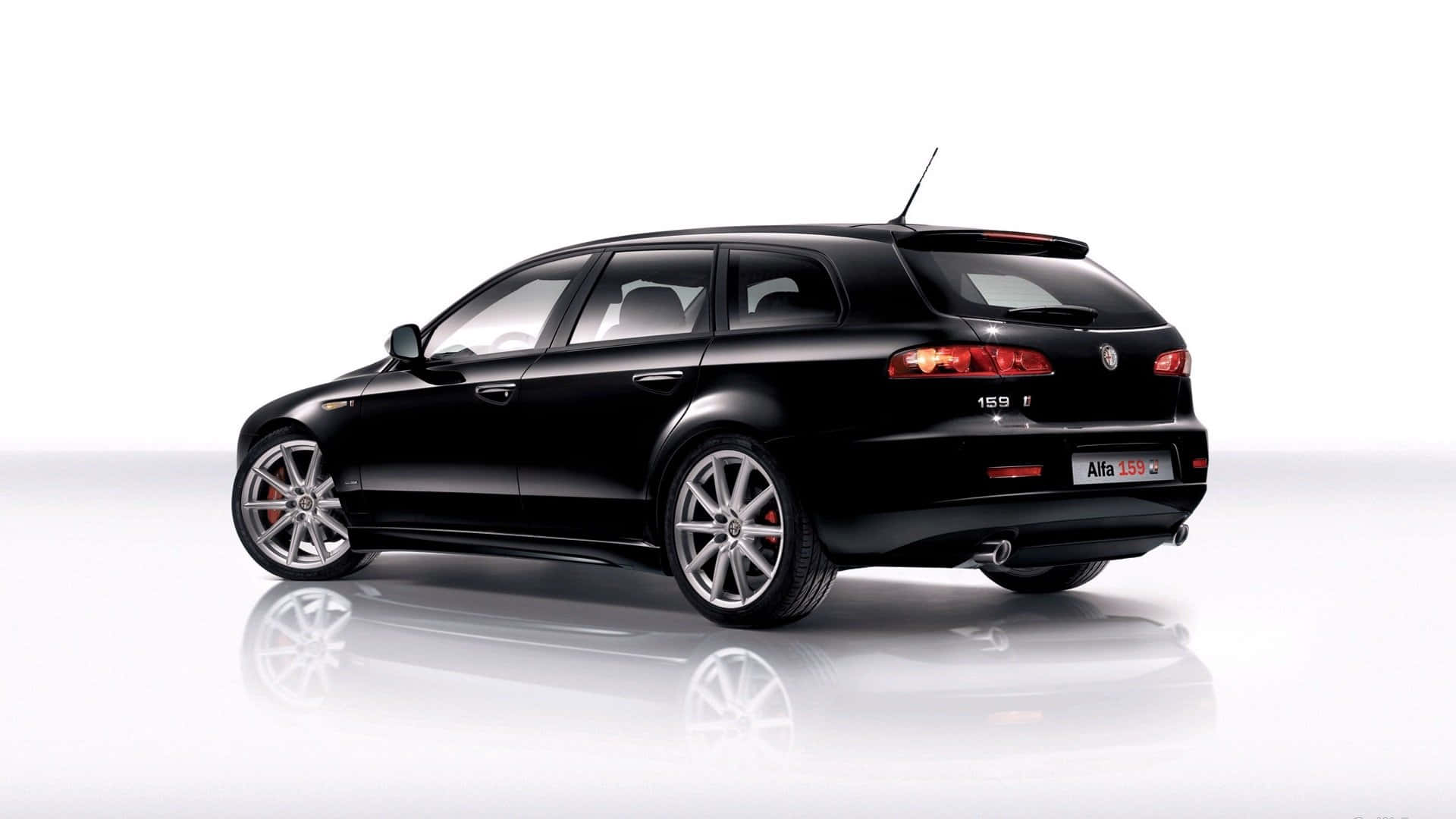 Alfa Romeo 159 桌布 壁紙 — 一輛時尚的黑色Alfa 159旅行車在攝影棚燈光下閃耀，配備紅色尾燈和銀色合金輪圈，停在反光的白色表面上。