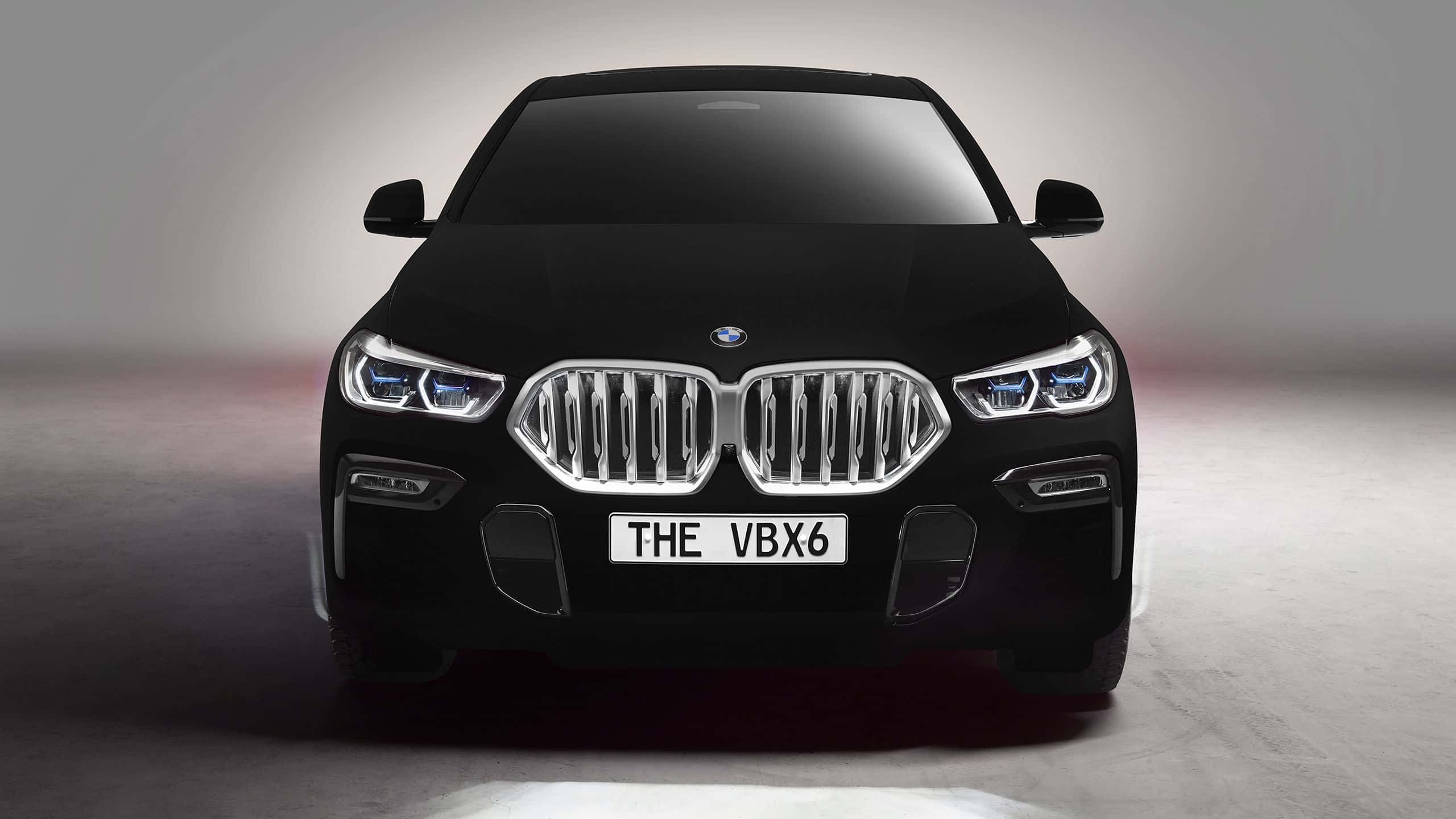 Vantablack 桌布 壁紙 — 一輛時尚的黑色BMW SUV正面朝前，配備發光頭燈和鍍鉻格柵，背景為簡約的工作室背景。