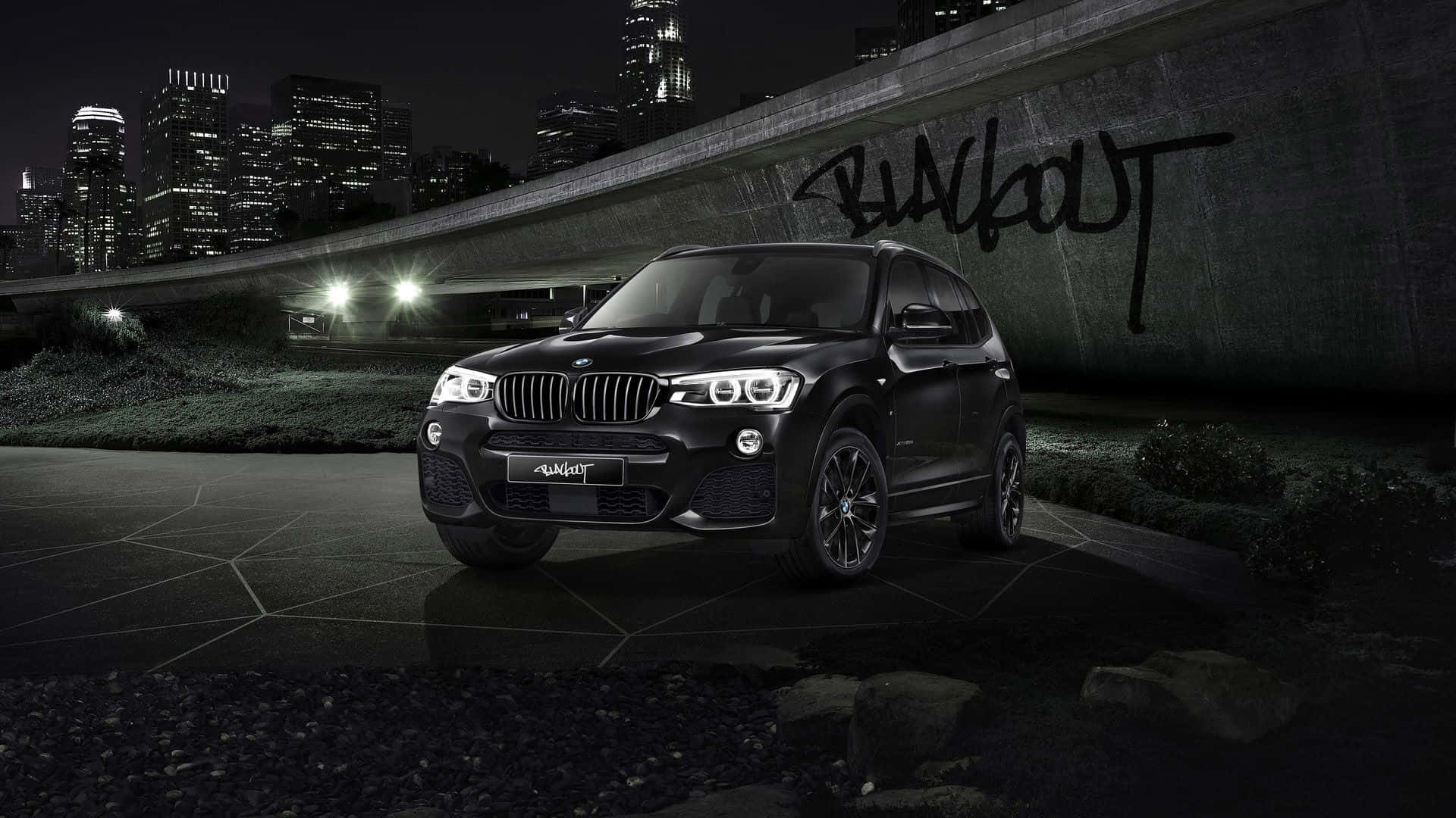 Bmw X3 桌布 壁紙 — 一輛時尚的黑色BMW X3停在一個佈滿塗鴉的天橋下，背後是夜晚閃爍的城市天際線。
