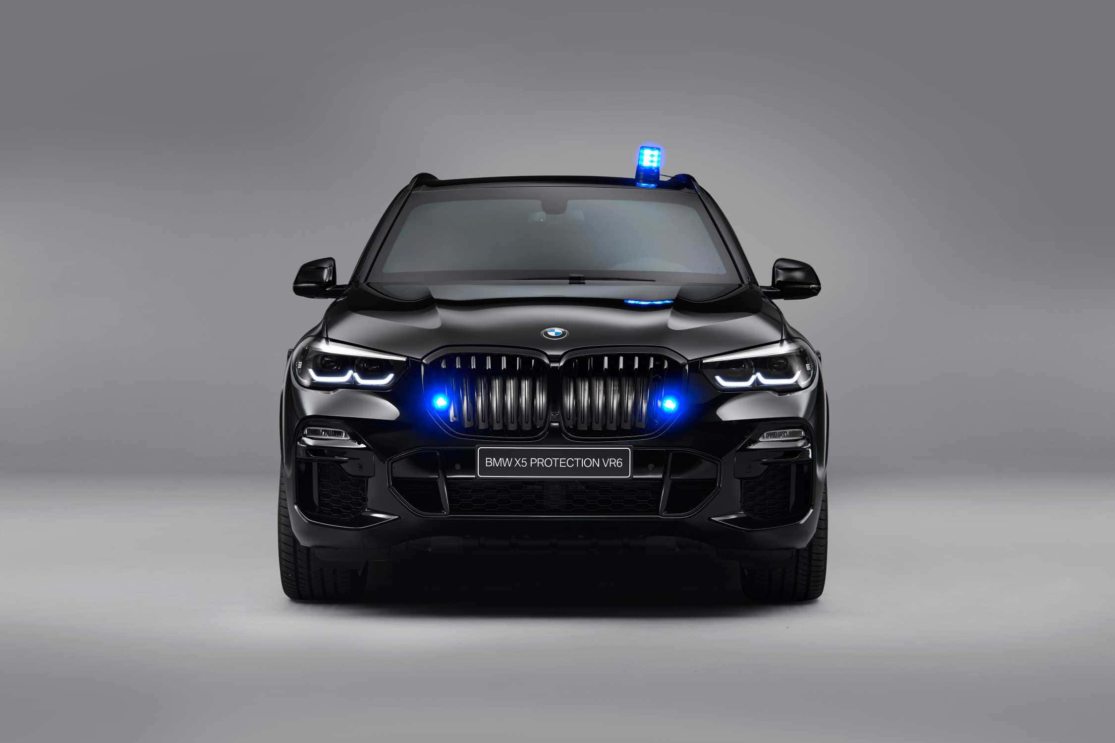 Bmw X5 桌布 壁紙 — 一輛時尚的黑色BMW X5 Protection VR6 SUV，在灰色工作室背景前，其格柵和車頂上閃爍著藍色緊急燈光。
