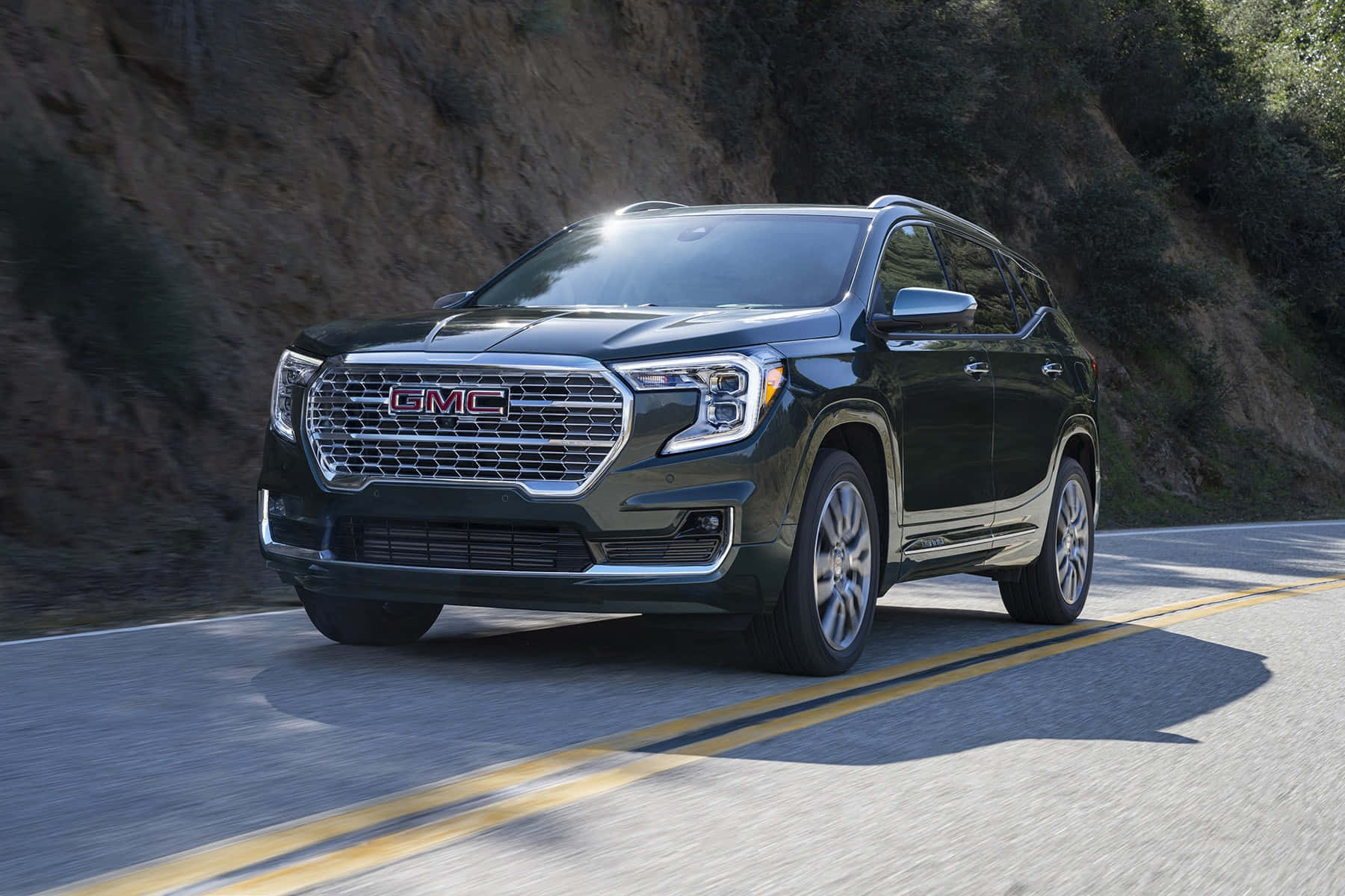 Gmc Terrain 桌布 壁紙 — 一輛時尚的黑色GMC Acadia SUV在蜿蜒的山路上行駛，背景有模糊的動態和陽光照射的懸崖。