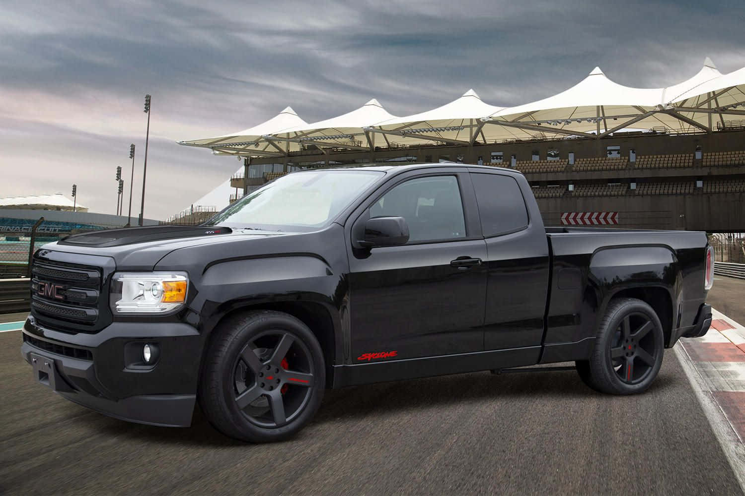 Gmc Syclone 桌布 壁紙 — 一輛時尚的黑色GMC Sierra AT4皮卡車，帶有紅色點綴，停在陰天下的賽道上。