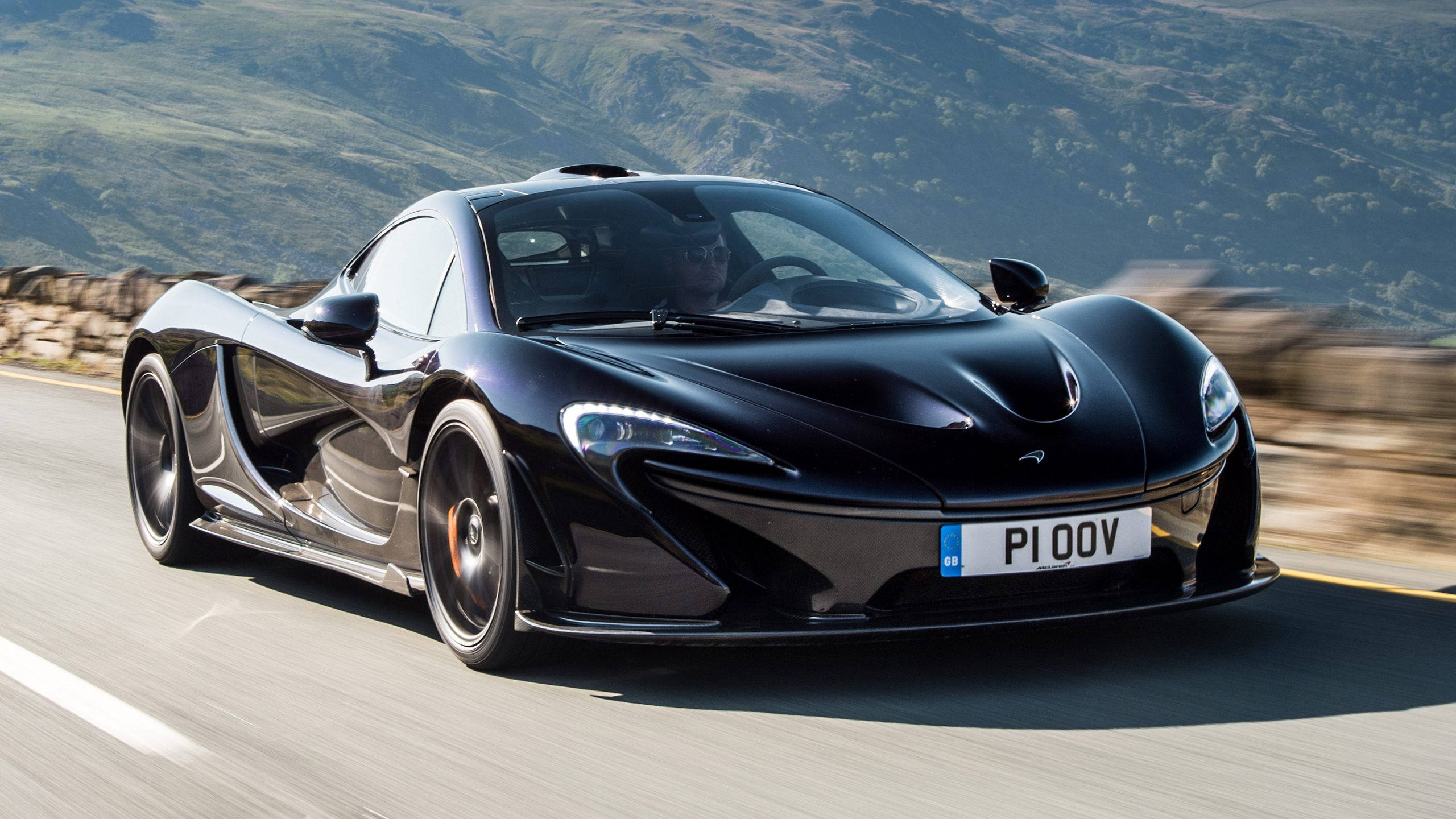 Sports Car 桌布 壁紙 — 一輛時尚的黑色McLaren P1超級跑車在蜿蜒的山路上奔馳，風景模糊。