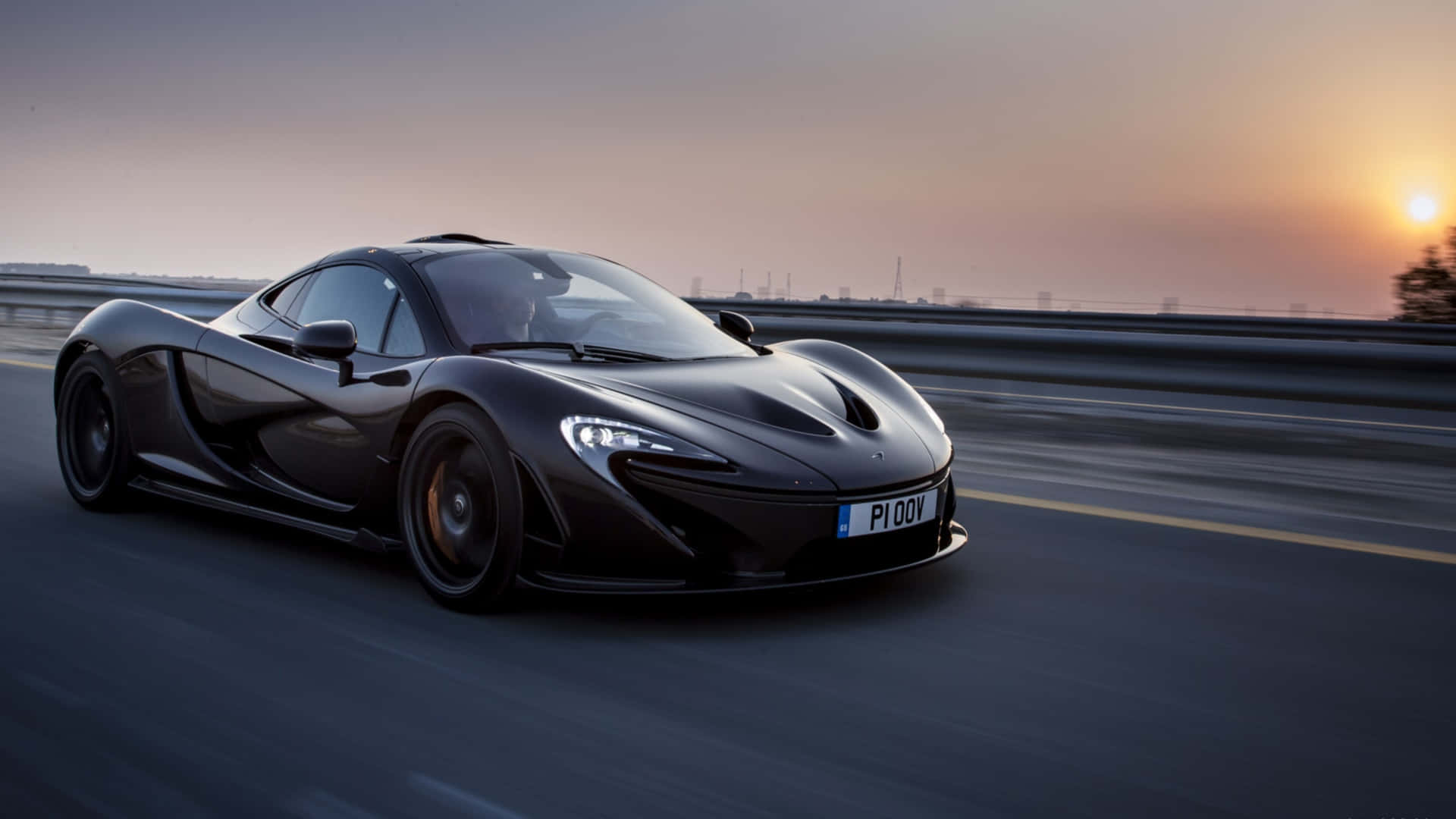 麥拿侖 桌布 壁紙 — 一輛時尚的黑色McLaren P1在日落時分沿高速公路疾馳，帶有模糊的動態和溫暖的天空色調。