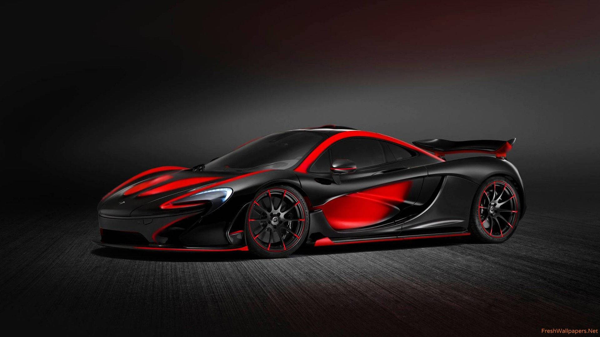 汽車 桌布 壁紙 — 一輛時尚的黑色McLaren跑車帶有醒目的紅色點綴，在戲劇性的攝影棚燈光下，在深色紋理地板上滑行。