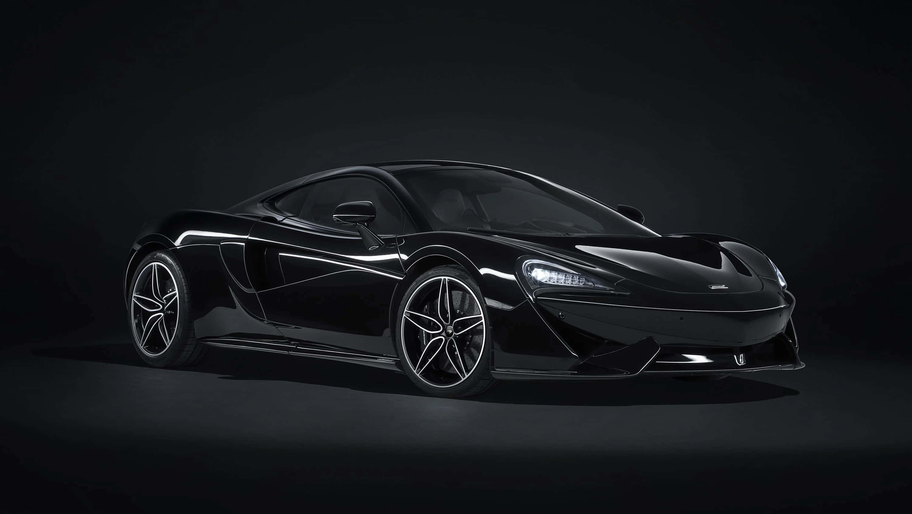 麥拿侖 桌布 壁紙 — 一輛時尚的黑色McLaren跑車在工作室燈光下，在黑暗背景中閃閃發光。