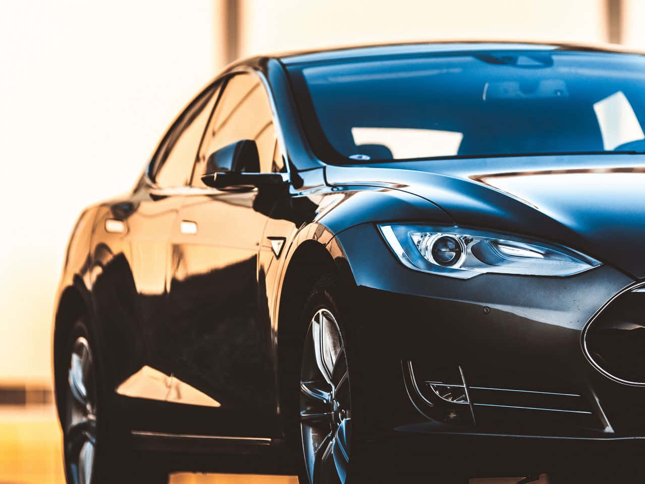 tesla 桌布 壁紙 — 一輛時尚的黑色Tesla汽車在溫暖的金色陽光下閃耀，拋光表面上有銳利的反射。