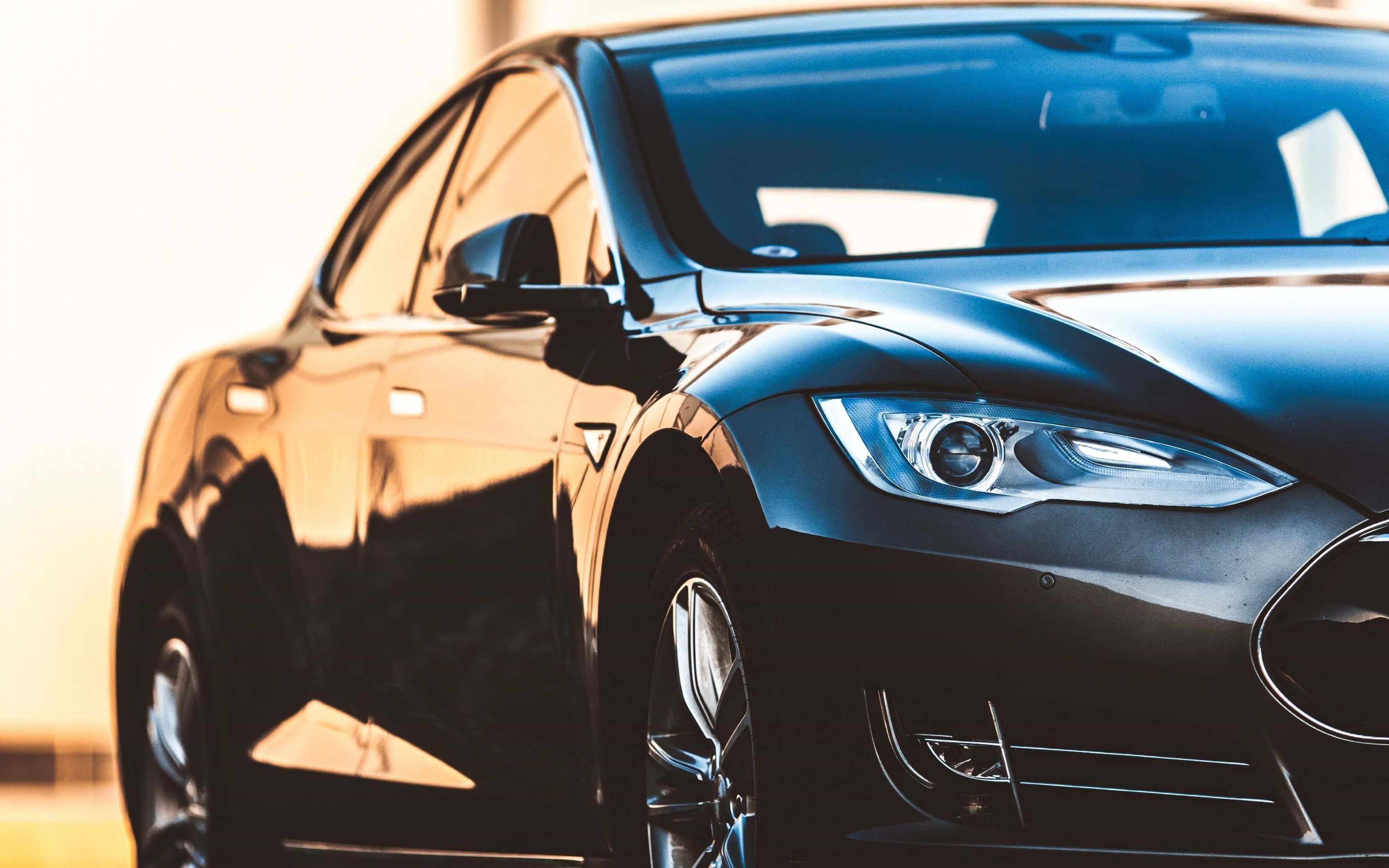 Hybrid Car 桌布 壁紙 — 一輛時尚的黑色Tesla汽車在溫暖的金色陽光下閃閃發光，拋光的表面上有銳利的反射。