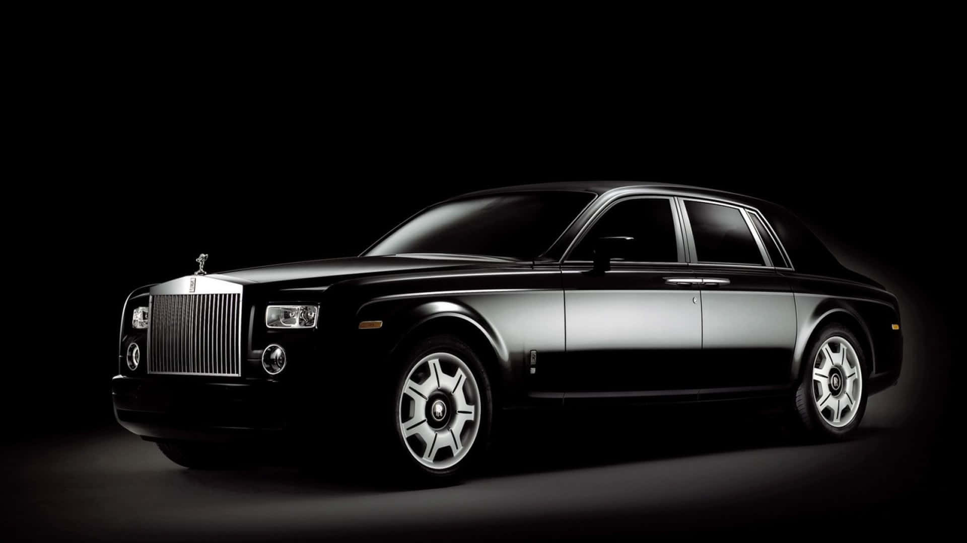 Rolls Royce 桌布 壁紙 — 一輛時尚的黑色勞斯萊斯幻影在純黑色背景下的攝影棚燈光中閃耀。