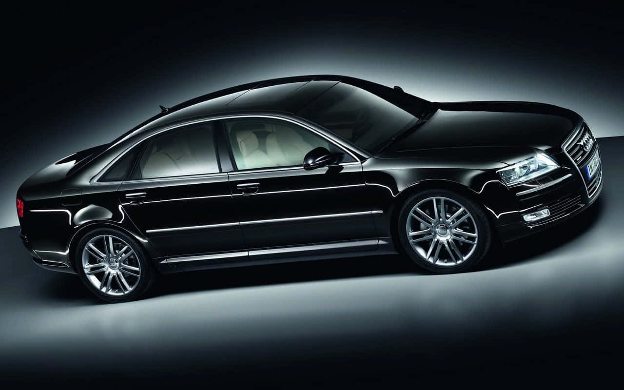 Audi S8 桌布 壁紙 — 一輛時尚的黑色奧迪轎車在戲劇性的工作室燈光下閃耀，配備銀色輪圈和光澤飾面。
