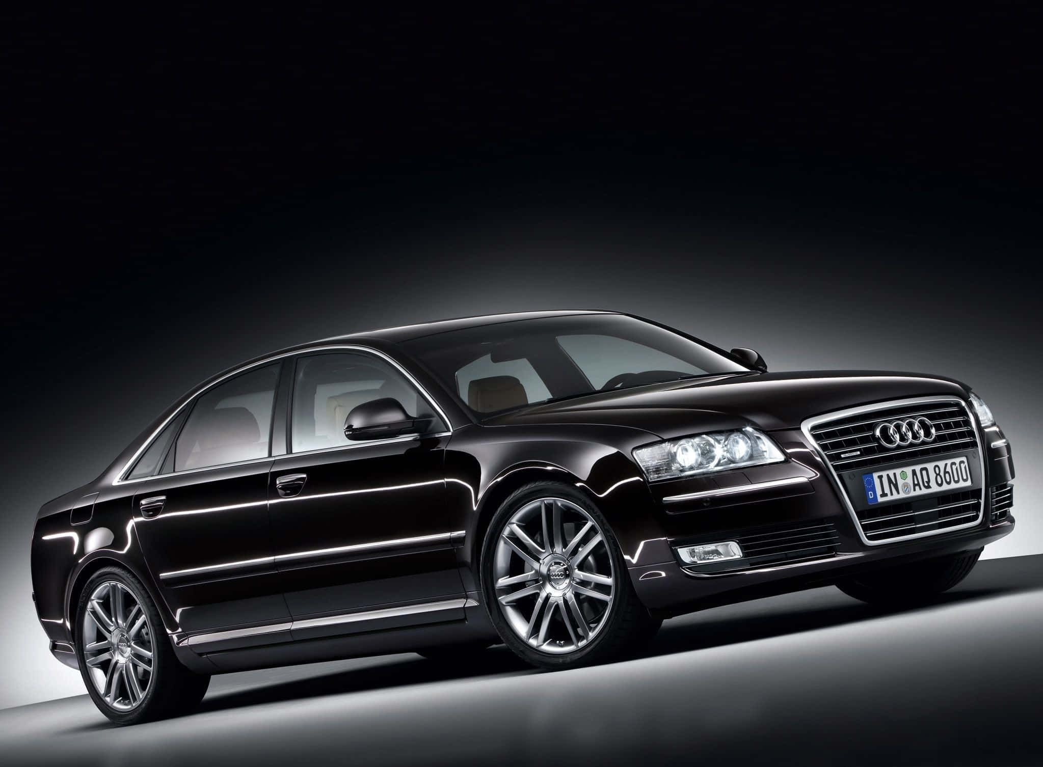 Audi S8 桌布 壁紙 — 一輛時尚的黑色奧迪轎車在攝影棚燈光下，於深色漸變背景前閃耀。