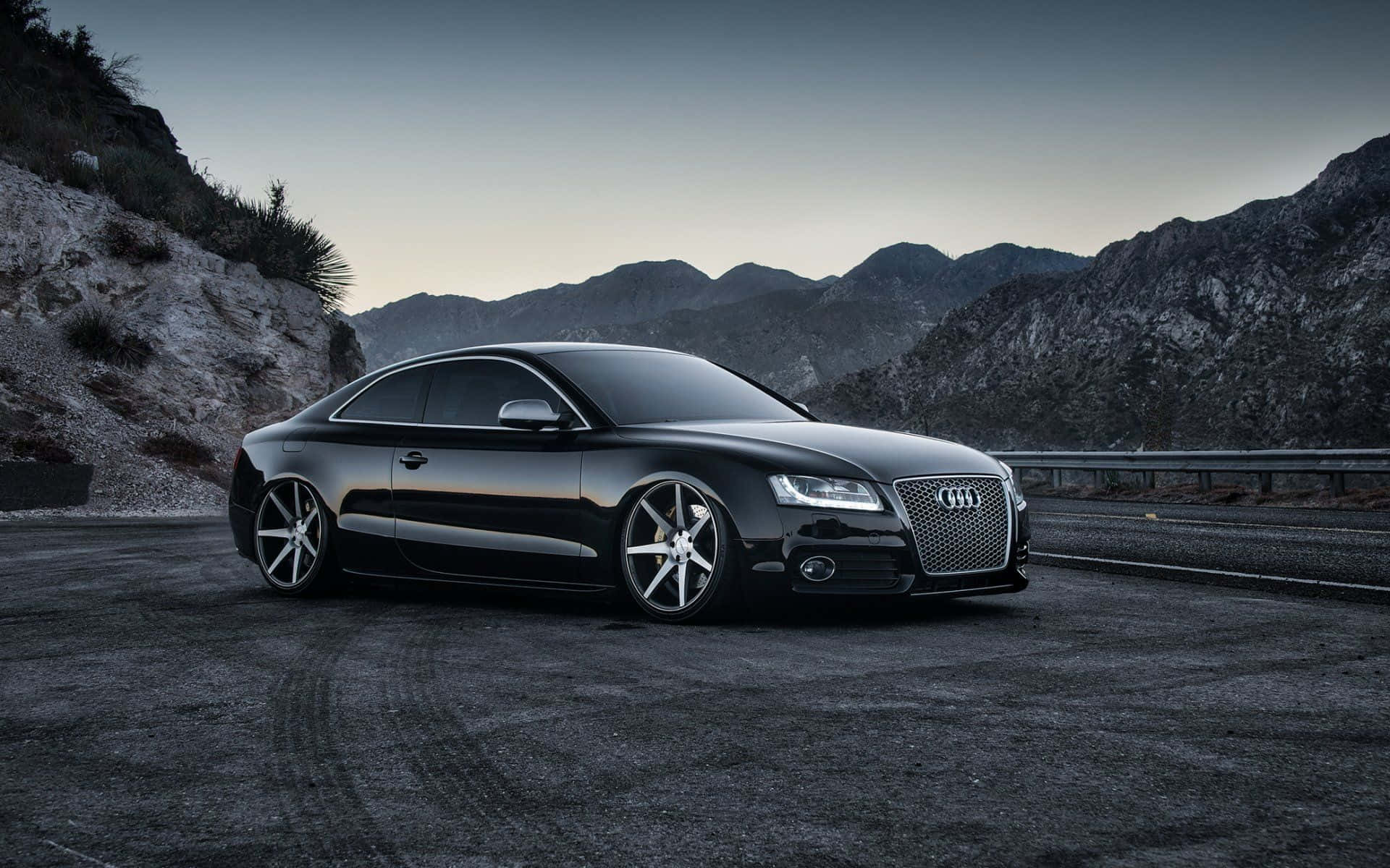 Audi S5 桌布 壁紙 — 一輛時尚的黑色奧迪雙門跑車在黃昏時停泊在山路上，背景是崎嶇的山峰。