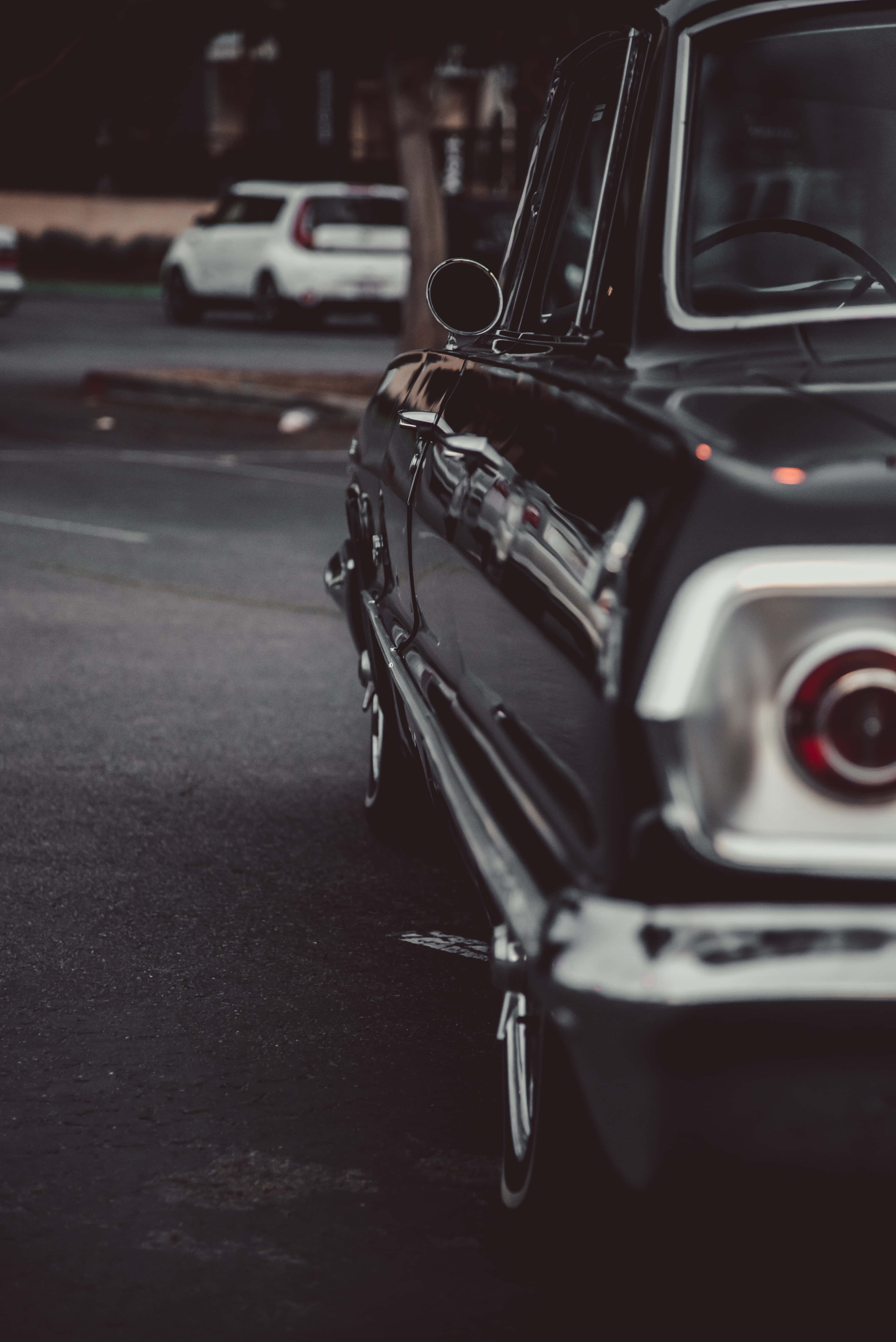 Black And White Vintage Car 桌布 壁紙 — 一輛時尚的黑色復古車停在燈光昏暗的街道上，背景中有一輛白色汽車模糊不清。