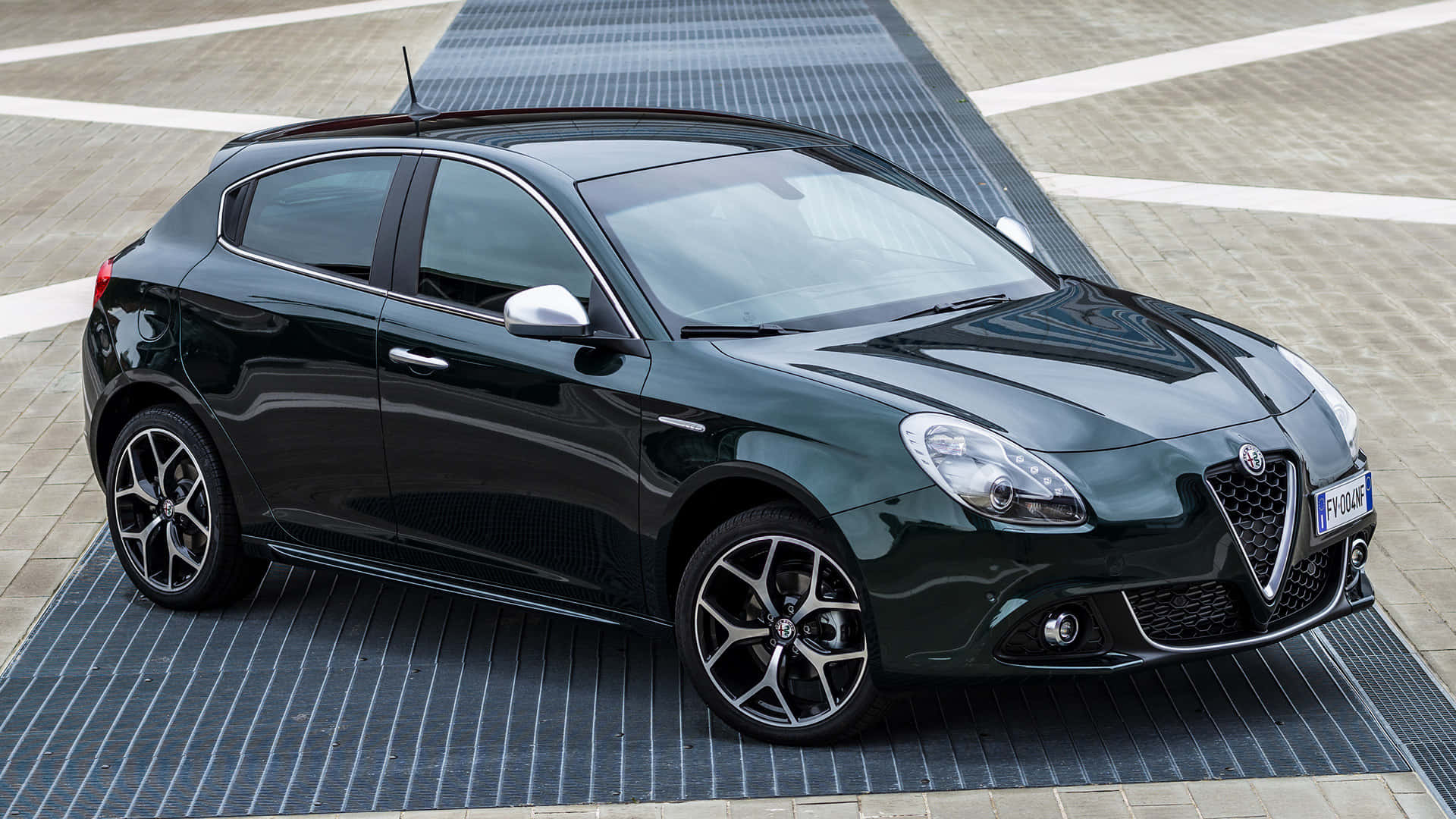 Alfa Romeo Giulietta 桌布 壁紙 — 一輛時尚的黑色愛快羅密歐Giulietta在明亮的日光下停泊在條紋路面上。