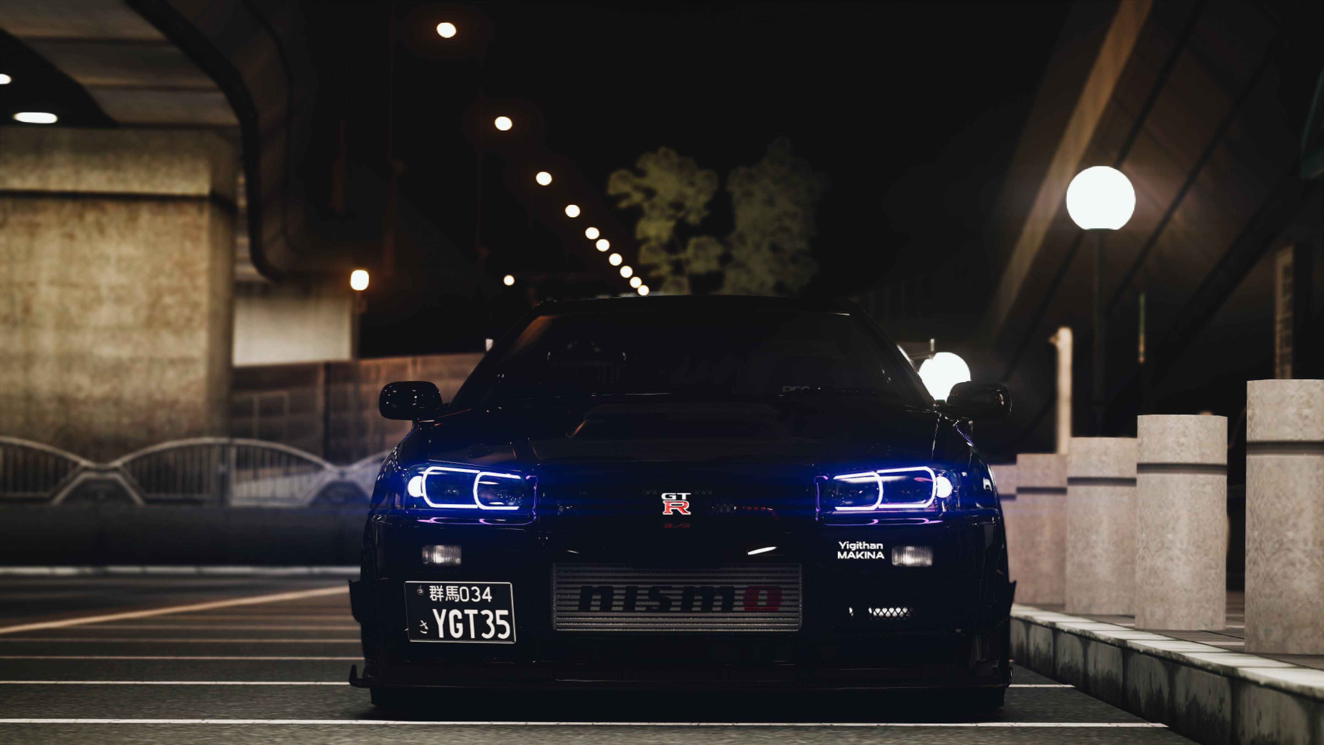 Nissan 桌布 壁紙 — 一輛時尚的黑色日產GT-R，帶有發光的藍色車頭燈，夜晚停放在昏暗的城市天橋下。