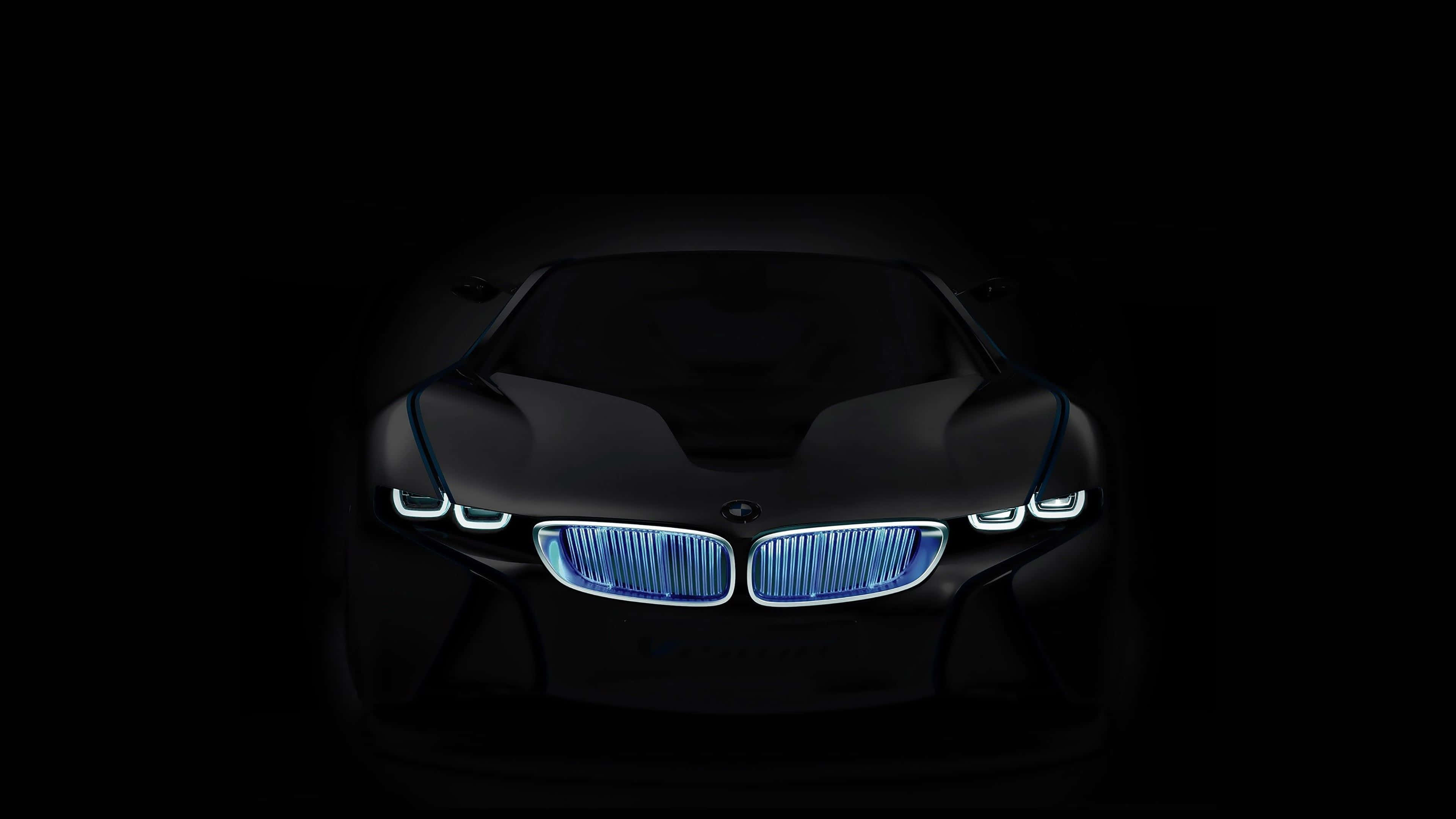 4K BMW 壁紙 桌布 壁紙 — 一輛時尚的黑色未來主義汽車在漆黑的背景下散發著充滿活力的藍色車頭燈。