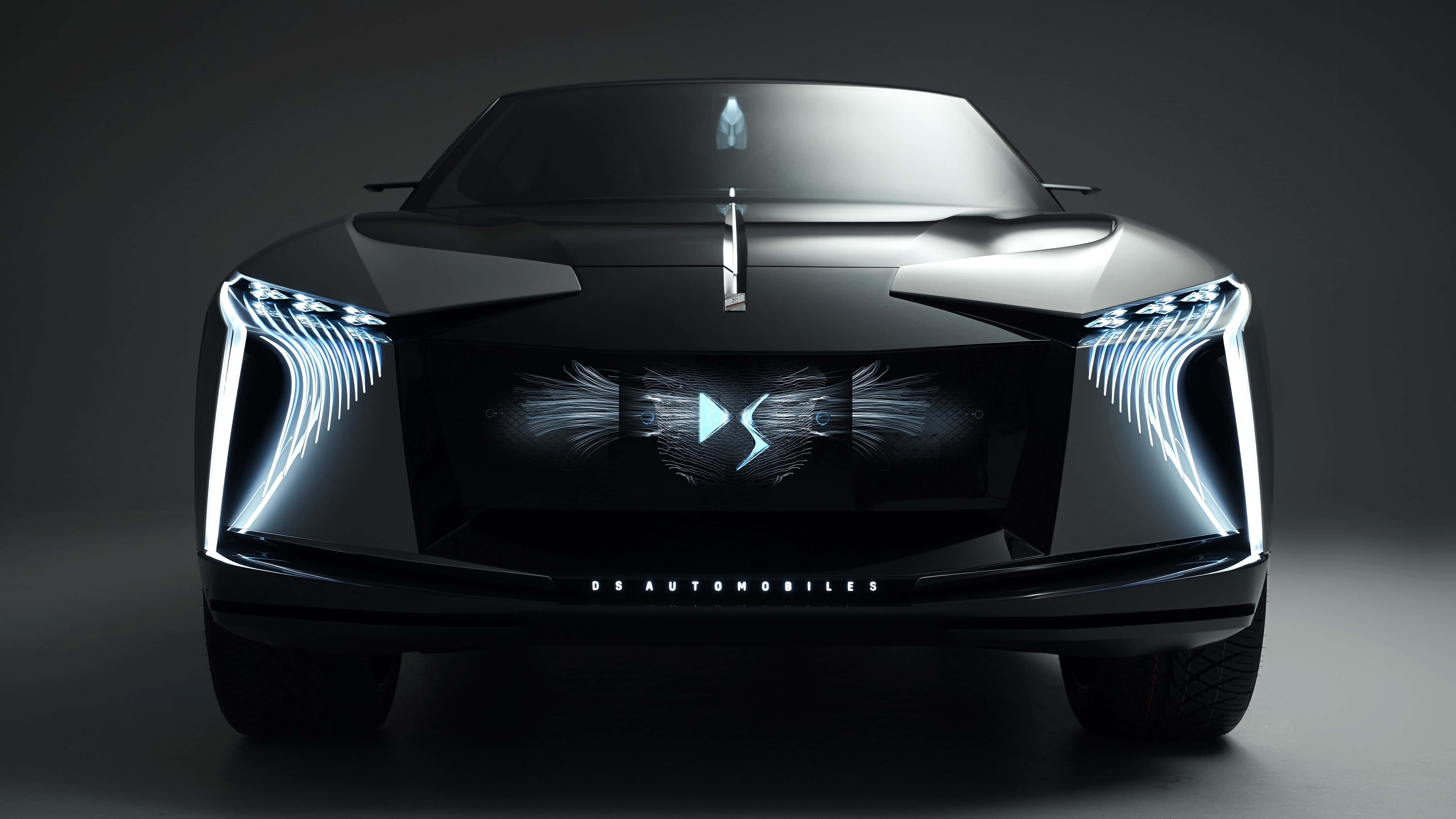 Ds Automobiles 桌布 壁紙 — 一輛時尚的黑色未來感汽車，帶有發光的藍色翼狀頭燈和車頭格柵上的數碼徽章。