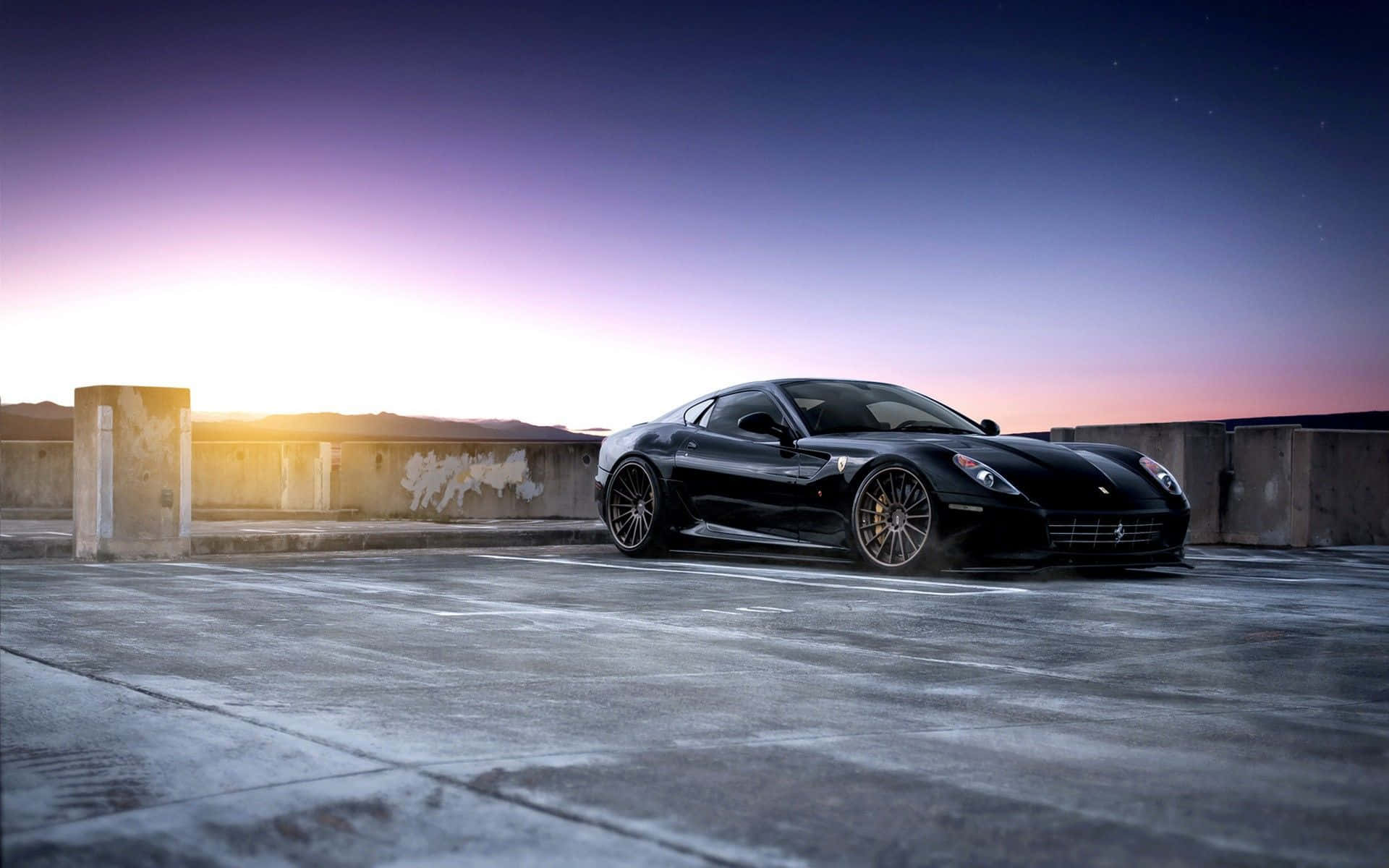 Ferrari 599 Gtb Fiorano 桌布 壁紙 — 一輛時尚的黑色法拉利跑車停放在混凝土屋頂上，夕陽西下，天空呈現鮮豔的紫色和橙色。