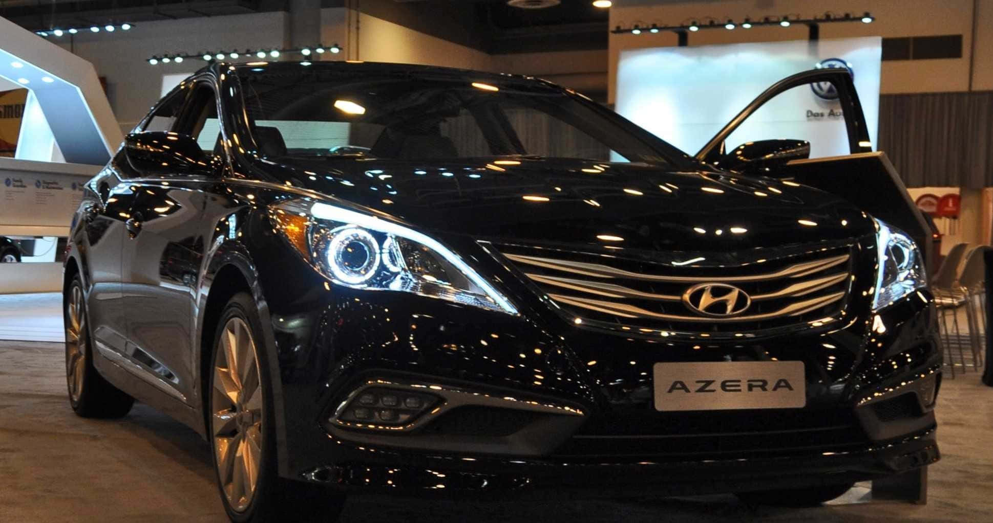 Hyundai Azera 桌布 壁紙 — 一輛時尚的黑色現代Azera轎車在明亮的展廳燈光下閃閃發光，駕駛座車門敞開。