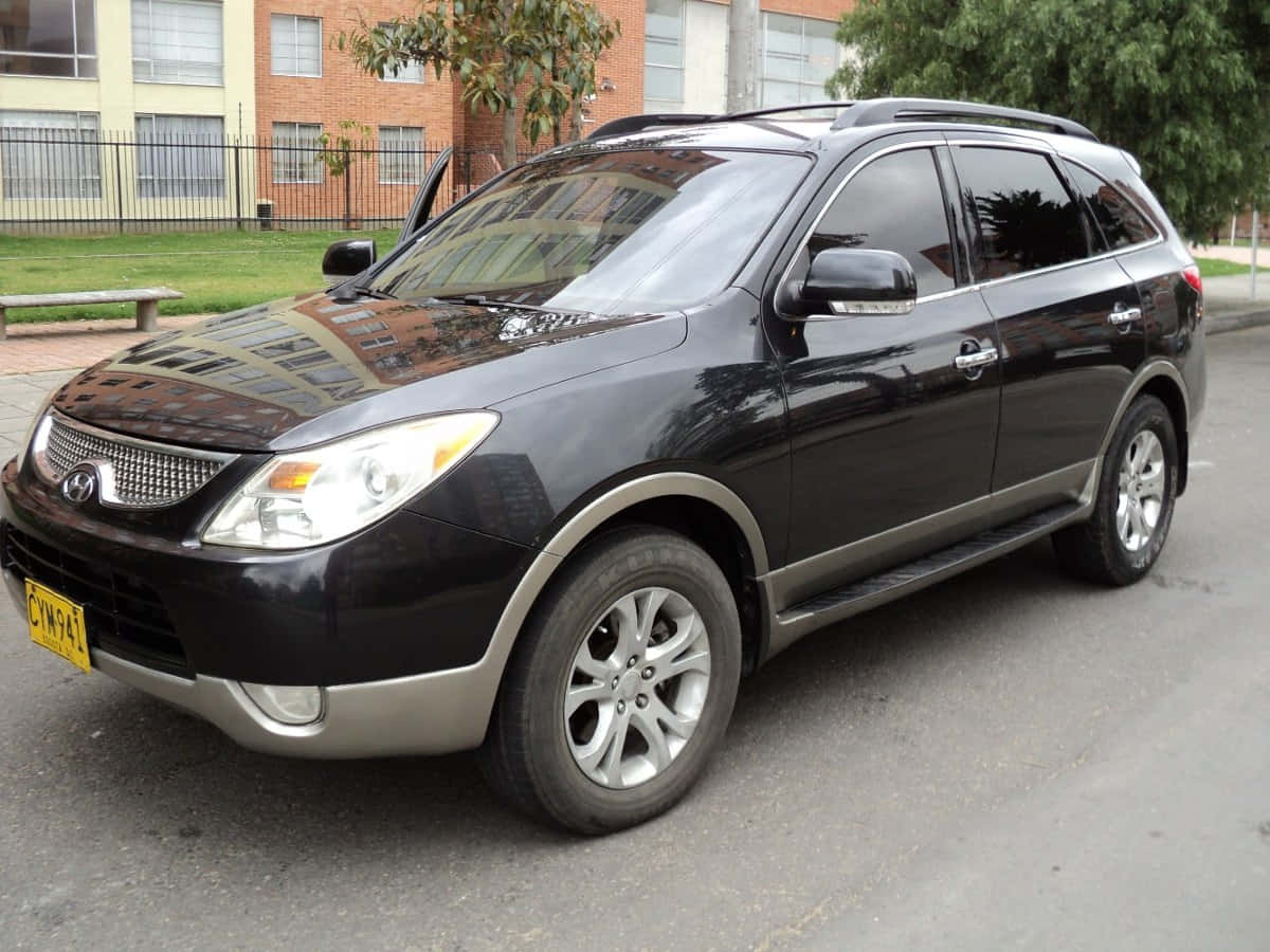 Hyundai Veracruz 桌布 壁紙 — 一輛時尚的黑色現代Santa Fe SUV停泊在城市的街道上，背景是磚砌建築和綠樹。