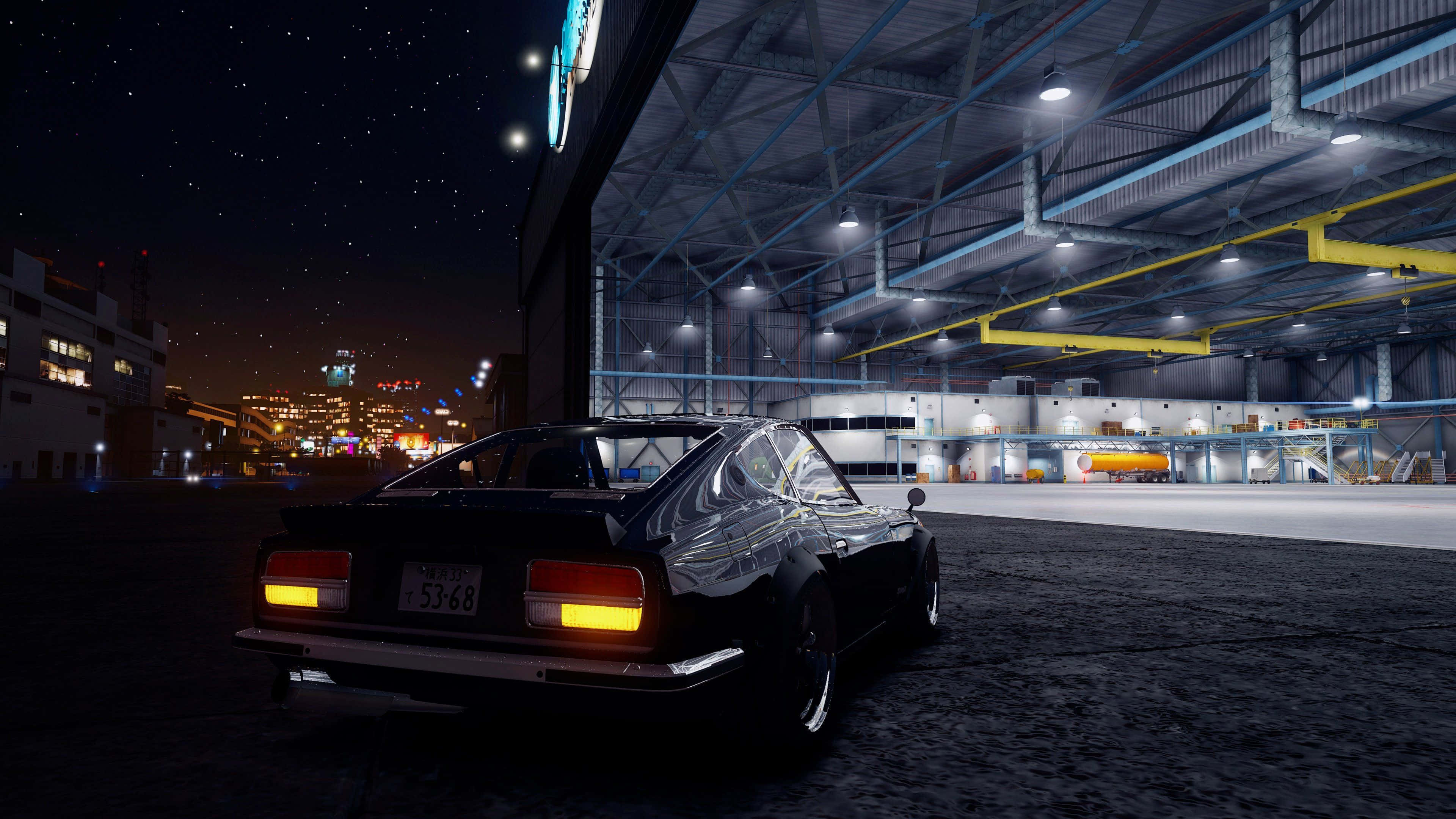 Gta V 4K 桌布 壁紙 — 一輛時尚的黑色經典跑車，帶有發光的尾燈，在星空下停在一個巨大的工業倉庫旁邊。