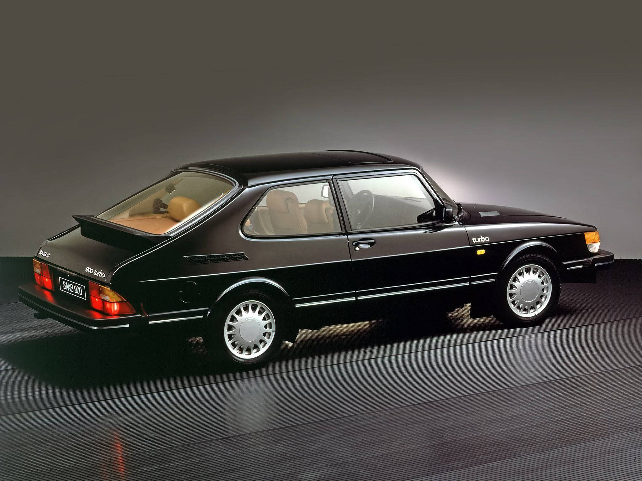 1978 Saab 900 Turbo 壁紙 — 一輛時尚的黑色薩博900 Turbo雙門轎跑車，配備米色內飾，在工作室中展示，帶有戲劇性燈光和反射地板。
