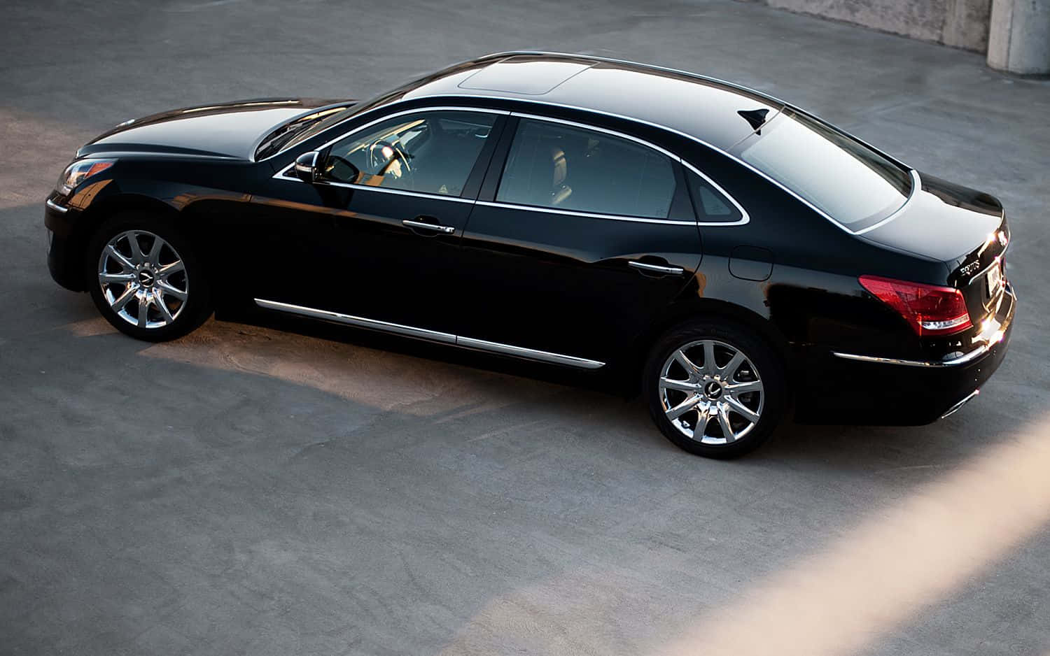 Hyundai Equus 桌布 壁紙 — 一輛時尚的黑色豪華轎車停在混凝土表面上，陽光投下長長的陰影。