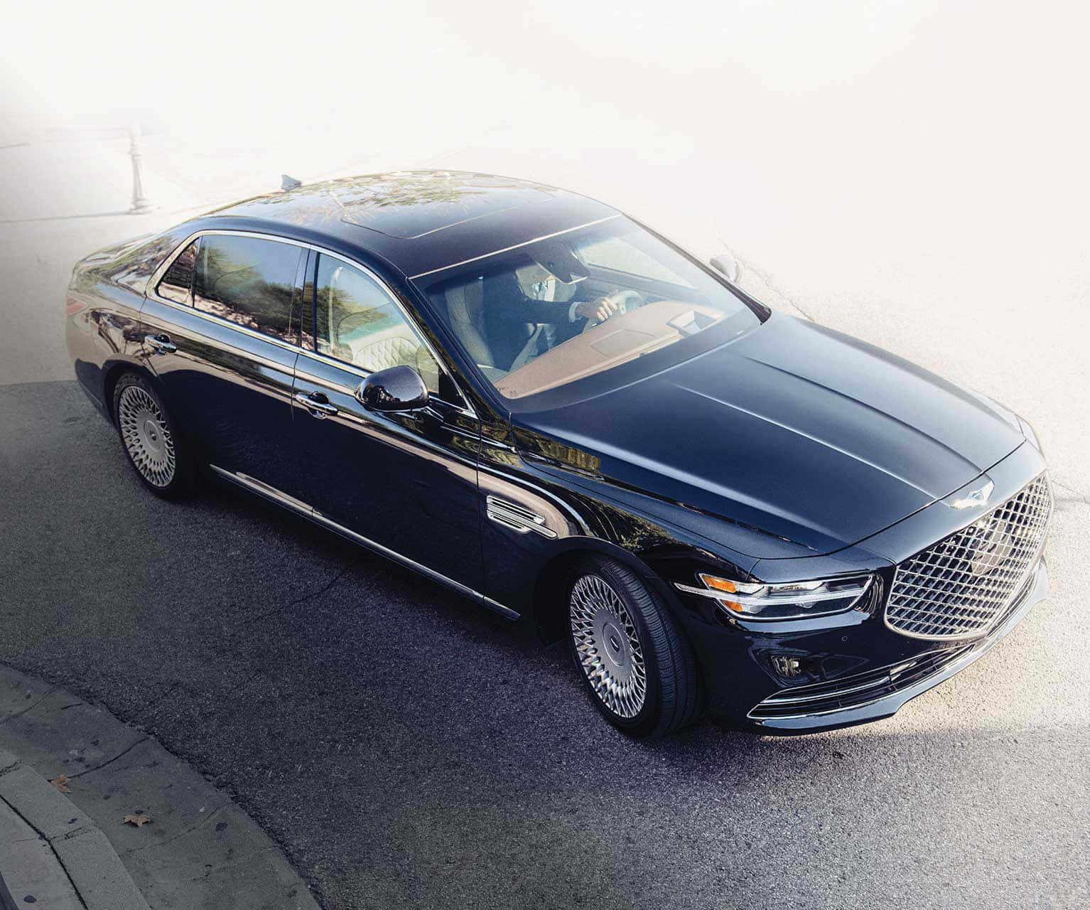 Genesis G90 桌布 壁紙 — 一輛時尚的黑色豪華轎車停在瀝青路上，司機在車內，陽光普照。