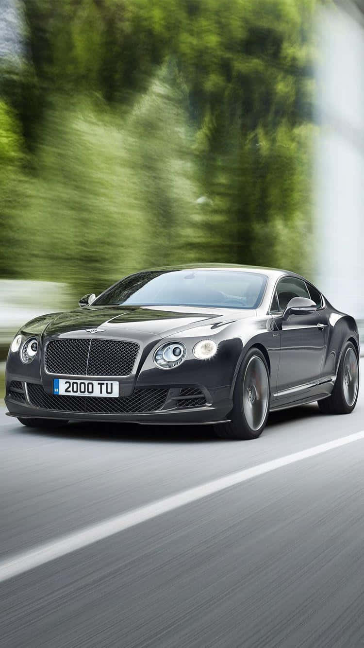 Convertible 桌布 壁紙 — 一輛時尚的黑色賓利 Continental GT 在道路上飛馳，兩旁茂密的綠樹因移動而模糊。