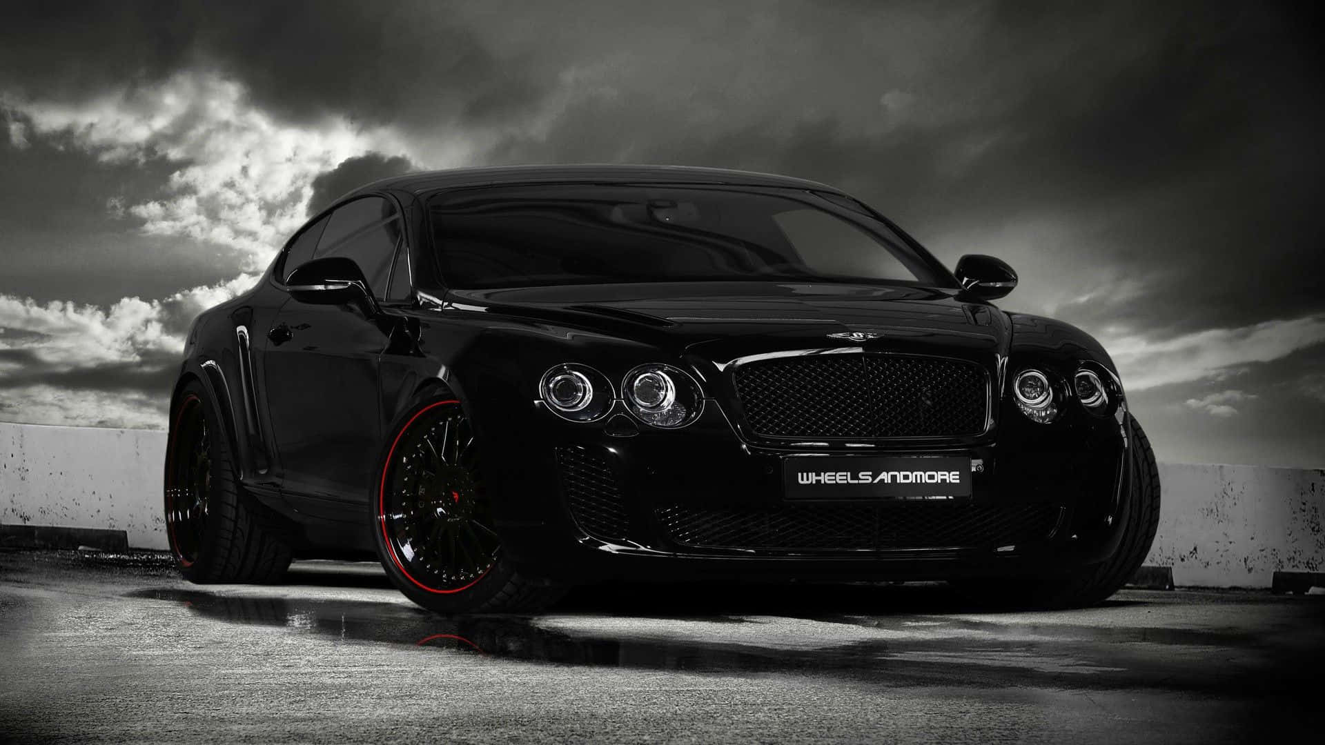 Black And White Car 桌布 壁紙 — 一輛時尚的黑色賓利 Continental GT，配備紅色點綴的輪圈，在戲劇性的暴風雨天空下，停在濕漉漉的路面上。