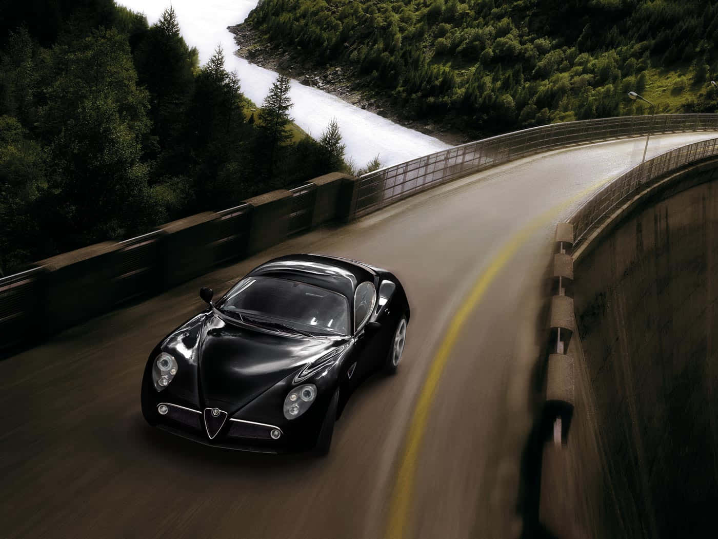 Alfa Romeo 8c Competizione 桌布 壁紙 — 一輛時尚的黑色跑車沿著蜿蜒的山路奔馳，旁邊是湍急的河流，穿過茂密的綠色森林。