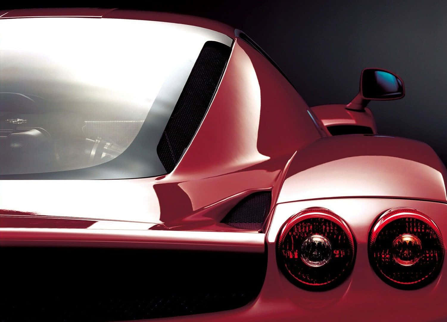 Ferrari Enzo 桌布 壁紙 — 一輛時尚紅色跑車的尾部在深色工作室背景下展示發光的圓形尾燈和反射曲線。
