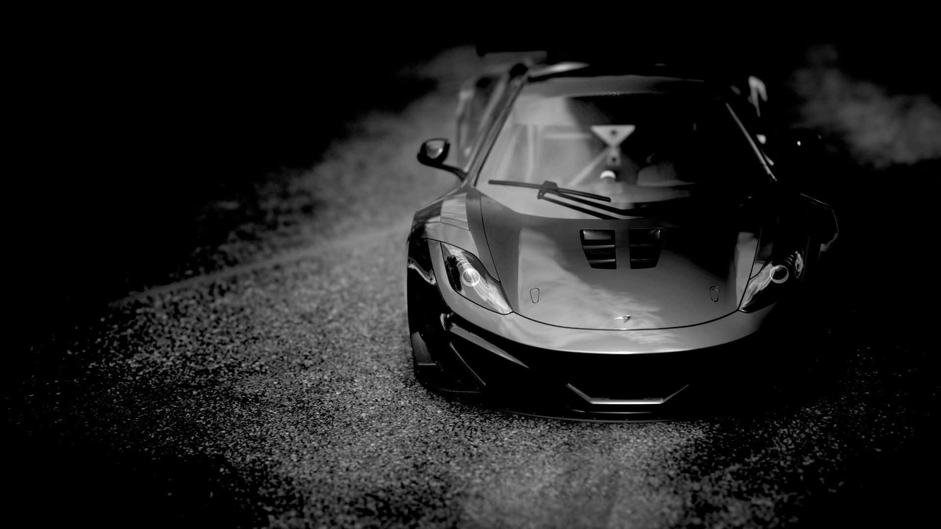 Black And White Car 桌布 壁紙 — 一輛時尚跑車在戲劇性的昏暗光線下，在碎石路上滑過迷霧般的黑暗。