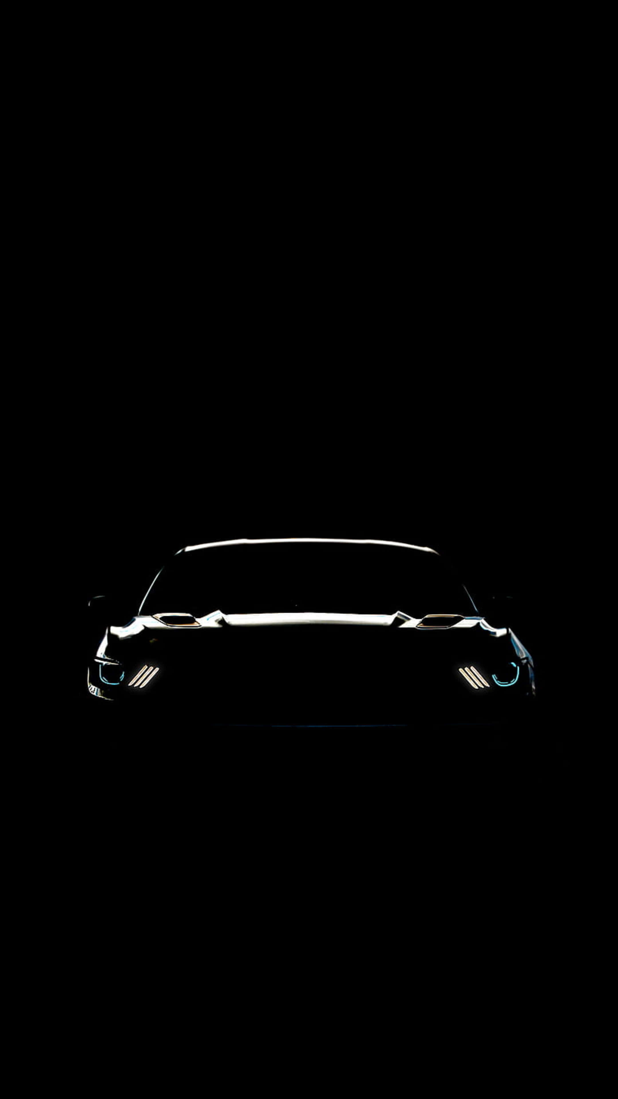 4K Car 桌布 壁紙 — 一輛時尚跑車的剪影在漆黑背景中閃爍著亮起的車頭燈。