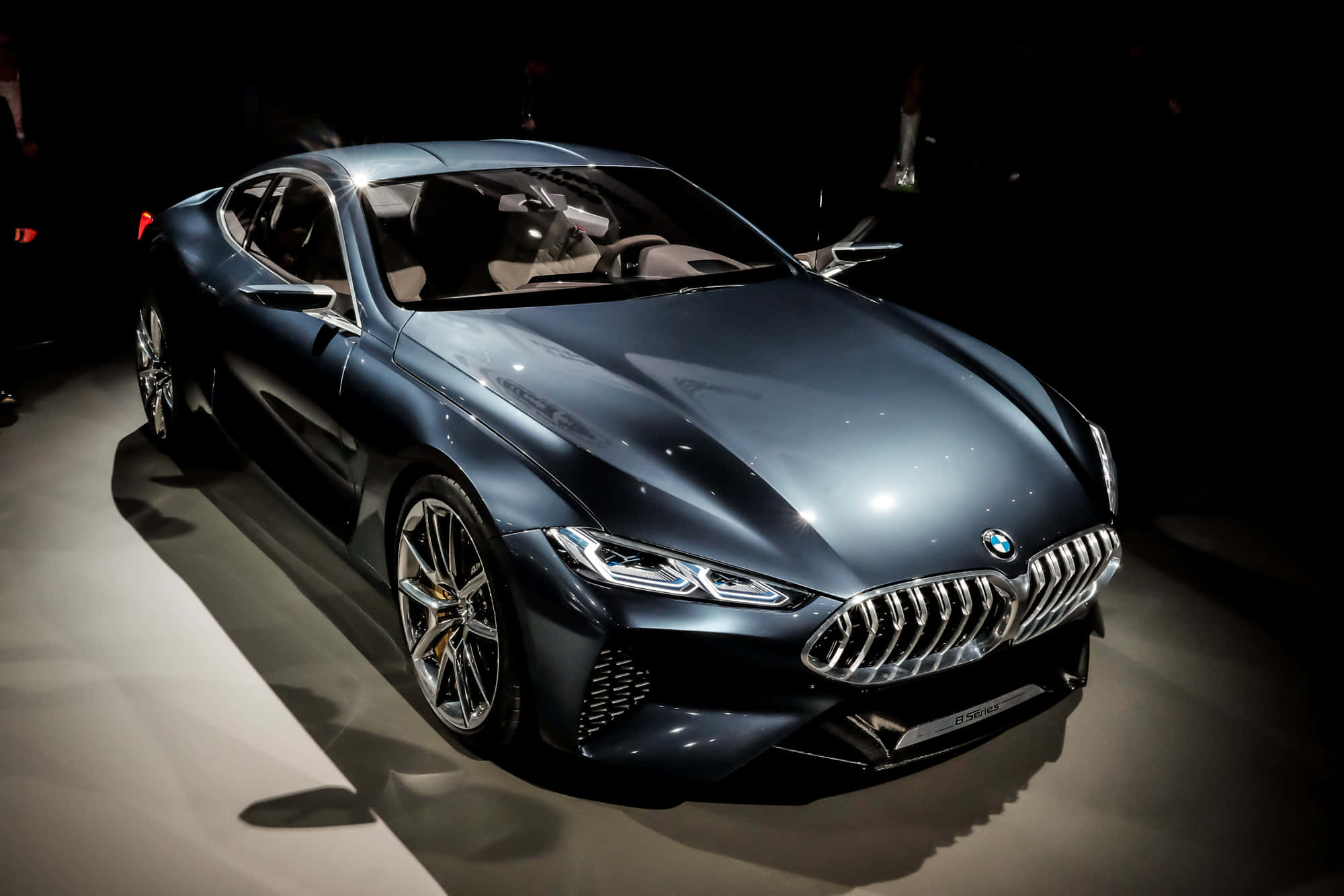 Bmw 8 Series 桌布 壁紙 — 一輛時尚金屬藍色BMW概念車在黑暗展廳的戲劇性聚光燈下閃耀。