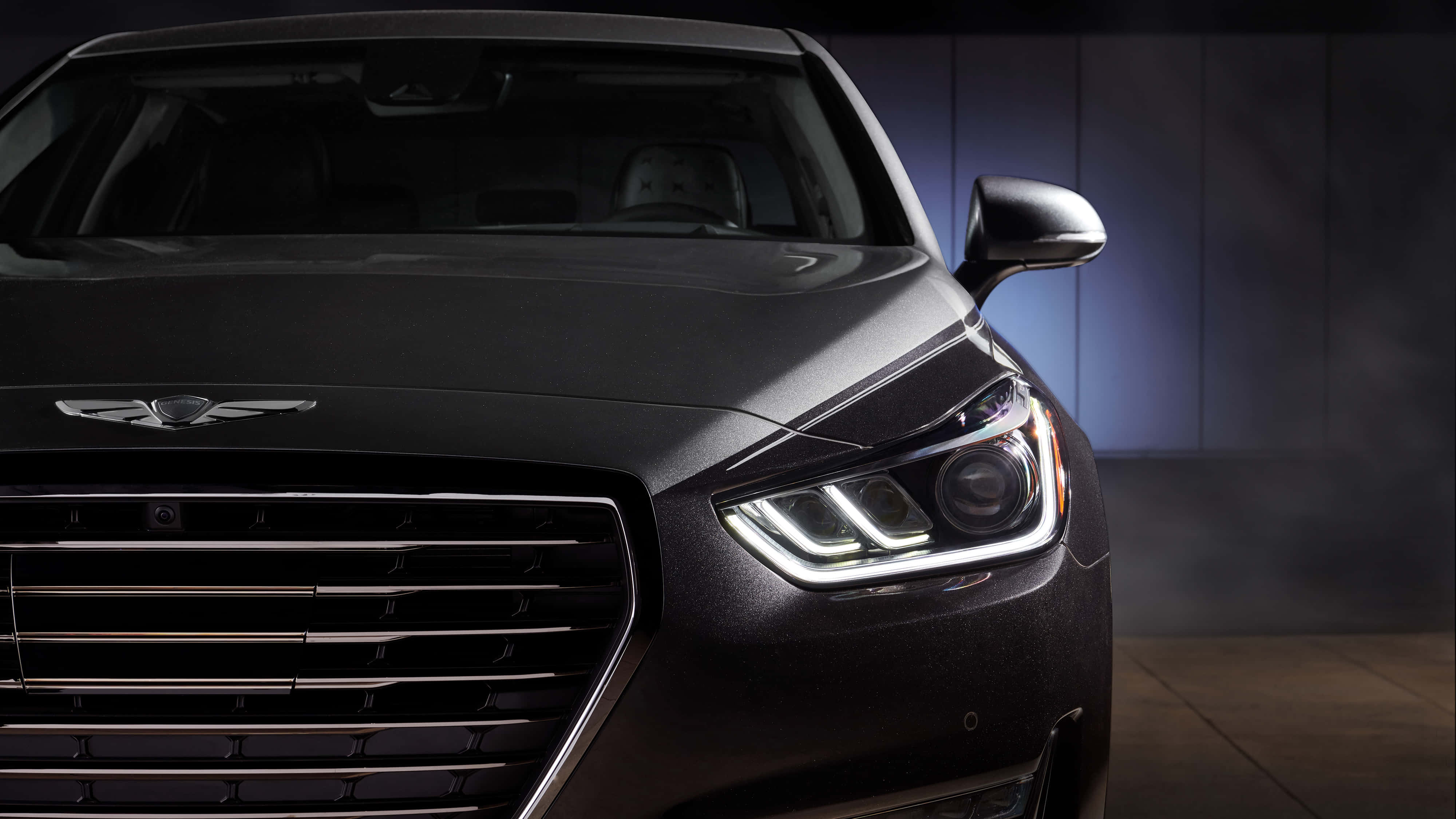 Genesis G90 桌布 壁紙 — 一輛時尚黑色豪華轎車的前臉在戲劇性的影樓燈光下閃耀，配備銳利的LED頭燈和鍍鉻格柵。