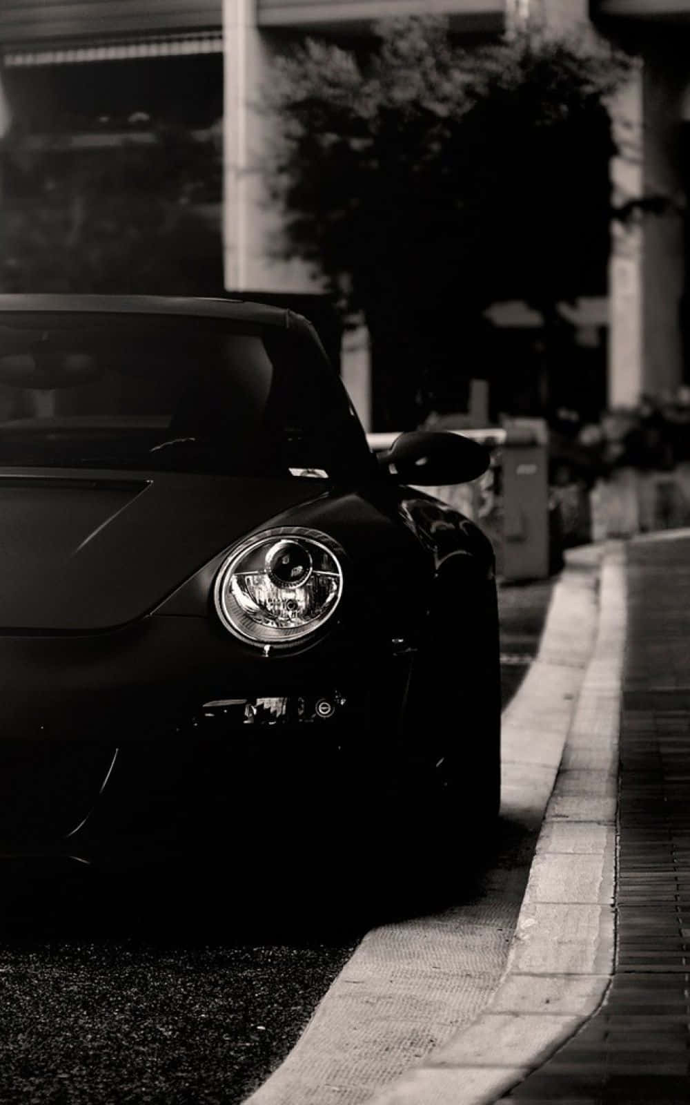 Black And White Car 桌布 壁紙 — 一輛時尚黑色跑車停泊在城市高架橋下的人行道上，帶有戲劇性的單色燈光。