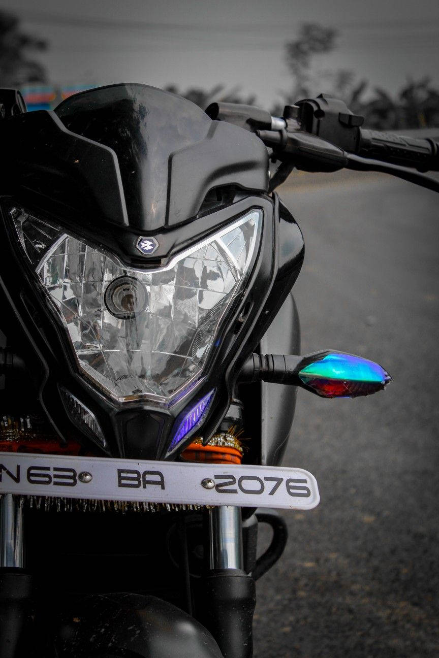 機車 桌布 壁紙 — 一輛時尚黑色電單車前部的特寫，帶有彩虹色指揮燈和鍍鉻前叉，背景是模糊的道路。