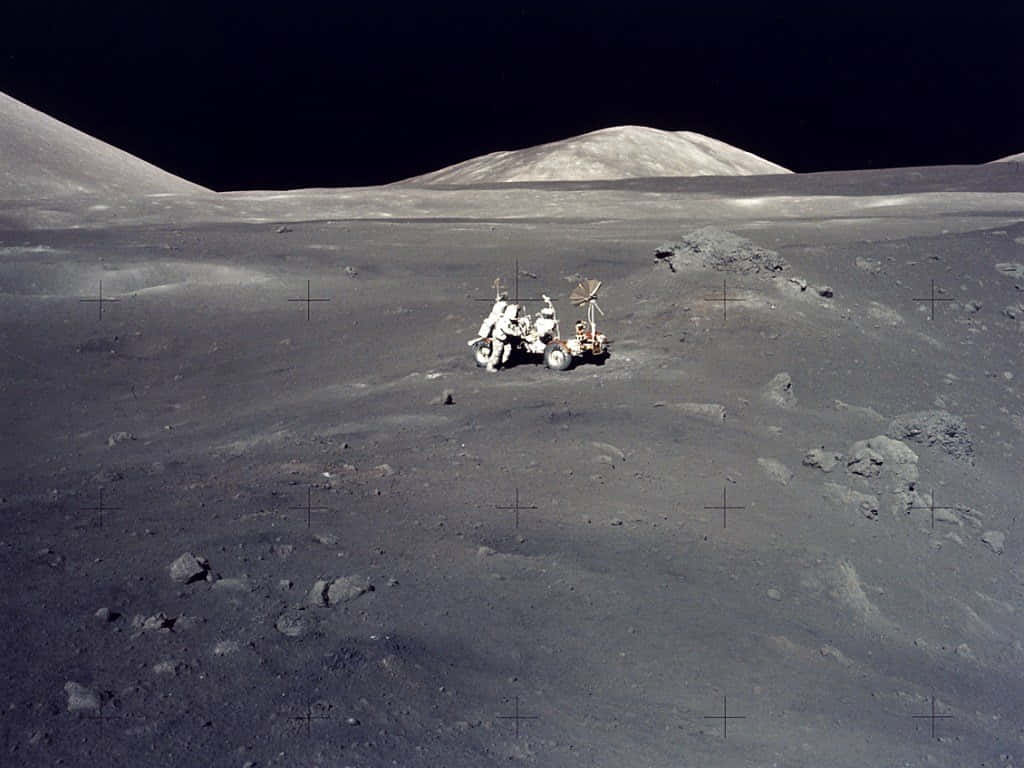 Space Mission 桌布 壁紙 — 一輛月球車和太空人在漆黑的天空和遠處山丘下探索荒蕪的灰色月球表面。