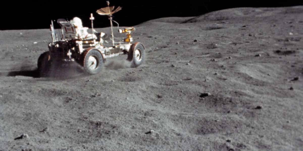 Lunar Rover 桌布 壁紙 — 一輛月球車在黑色天空下，行駛在月球灰色的塵土表面。