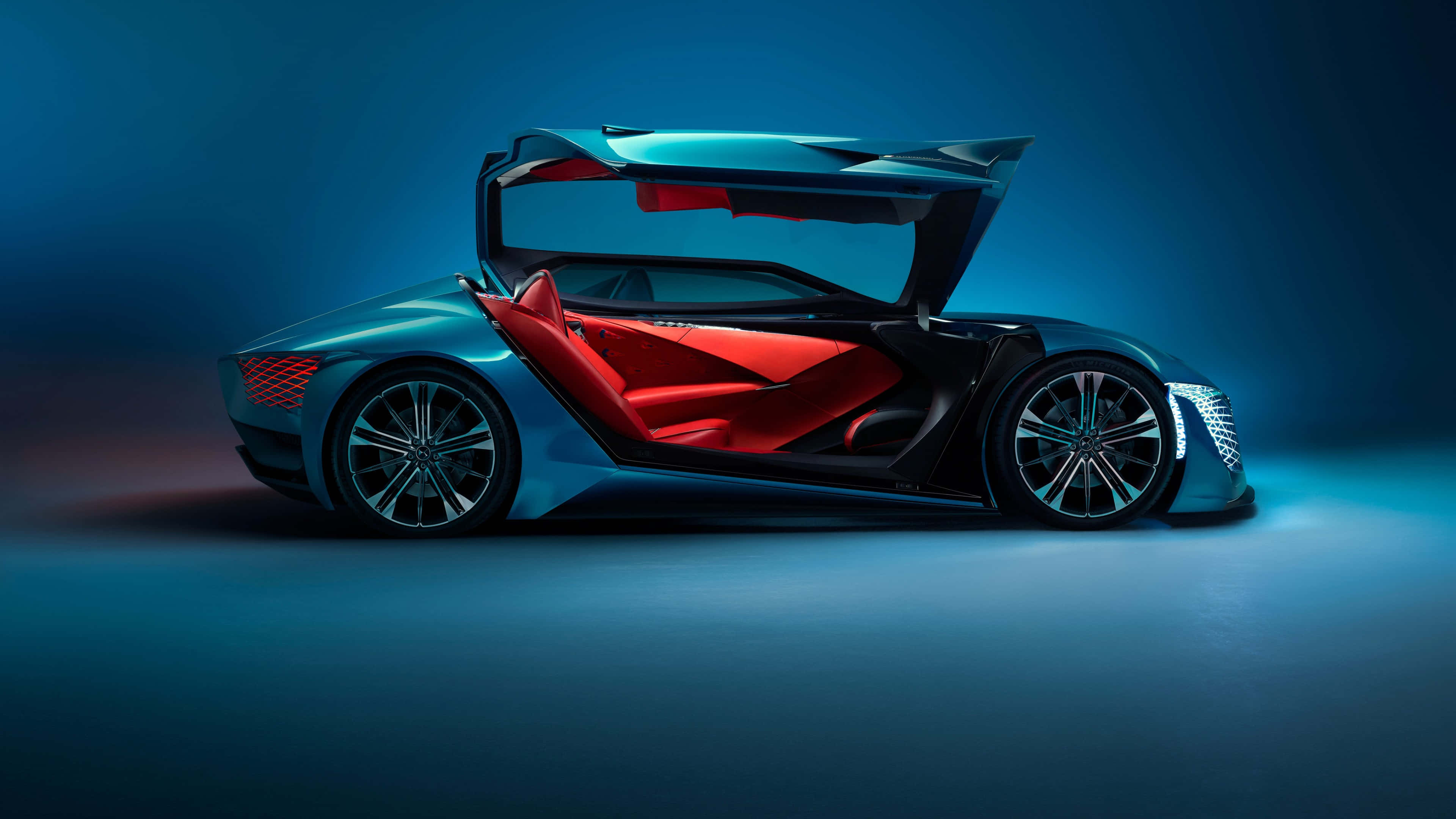 Ds Automobiles 桌布 壁紙 — 一輛未來主義的藍色跑車，紅色內飾，鷗翼門在戲劇性的藍色工作室燈光下打開。